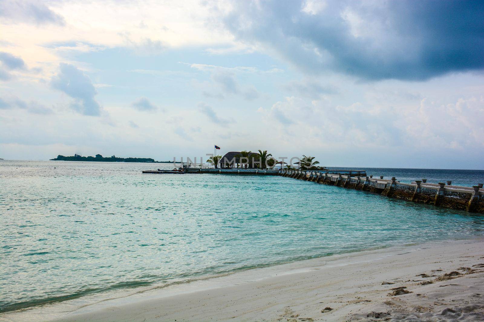 atoll of the tropics and maldives that are reflected in a sea of emerald with a cobalt blue sky