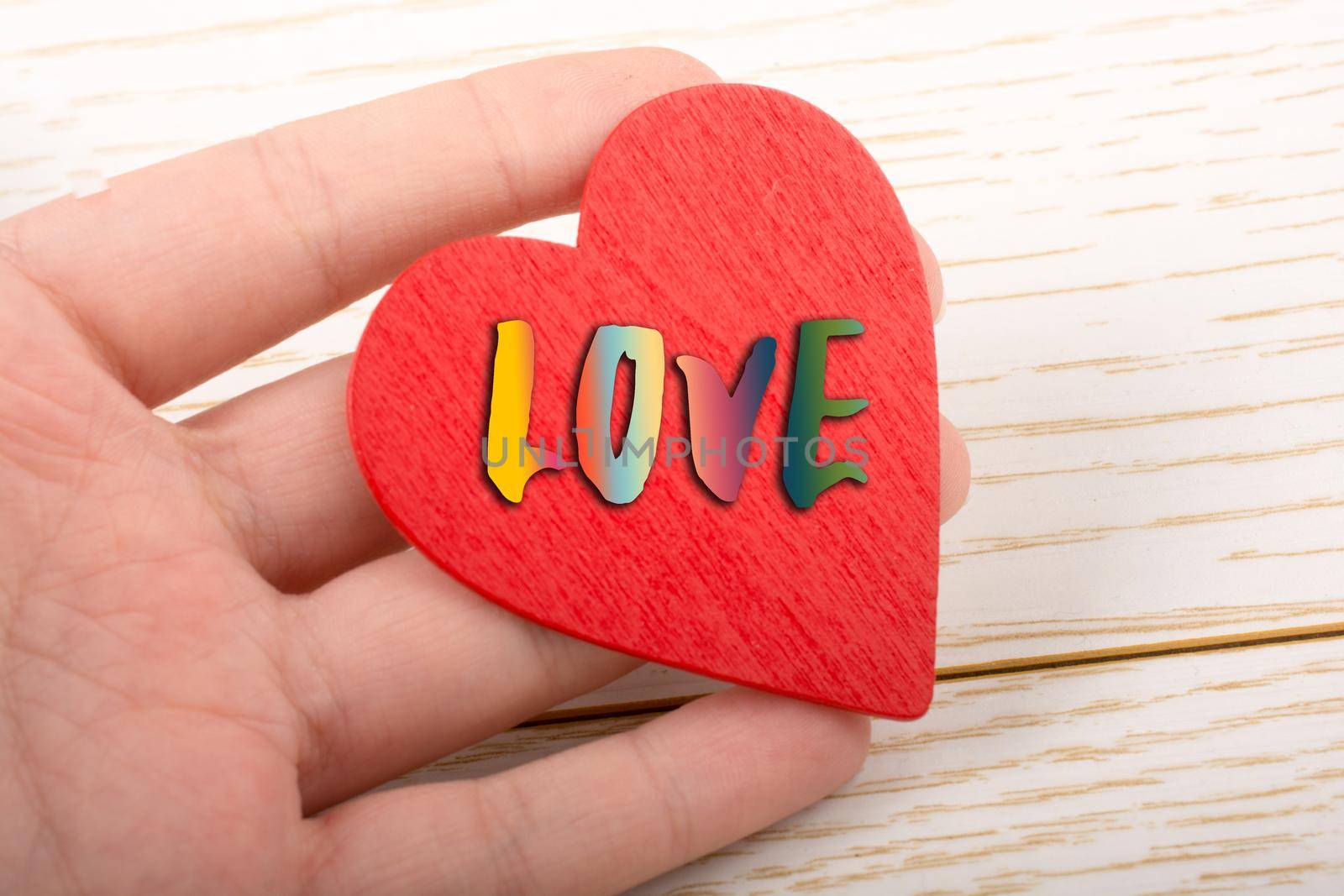 Red color heart  in hand on wooden texture