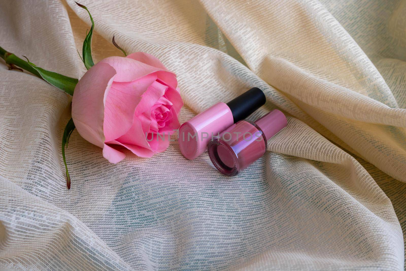 Pink rose and bottles of nail polish are on the pink tulle.