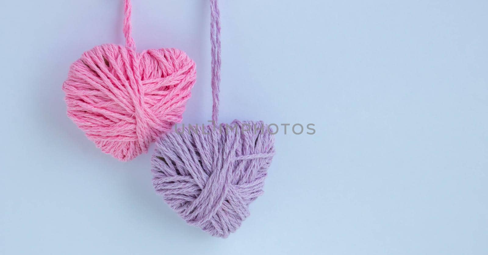Two thread hearts hang on a white background. Holiday card, background. The concept of Valentine's Day, March 8, Mother's Day.