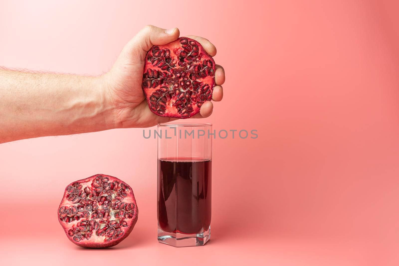 a hand squeezing juice from a pomegranate into a glass. High quality photo