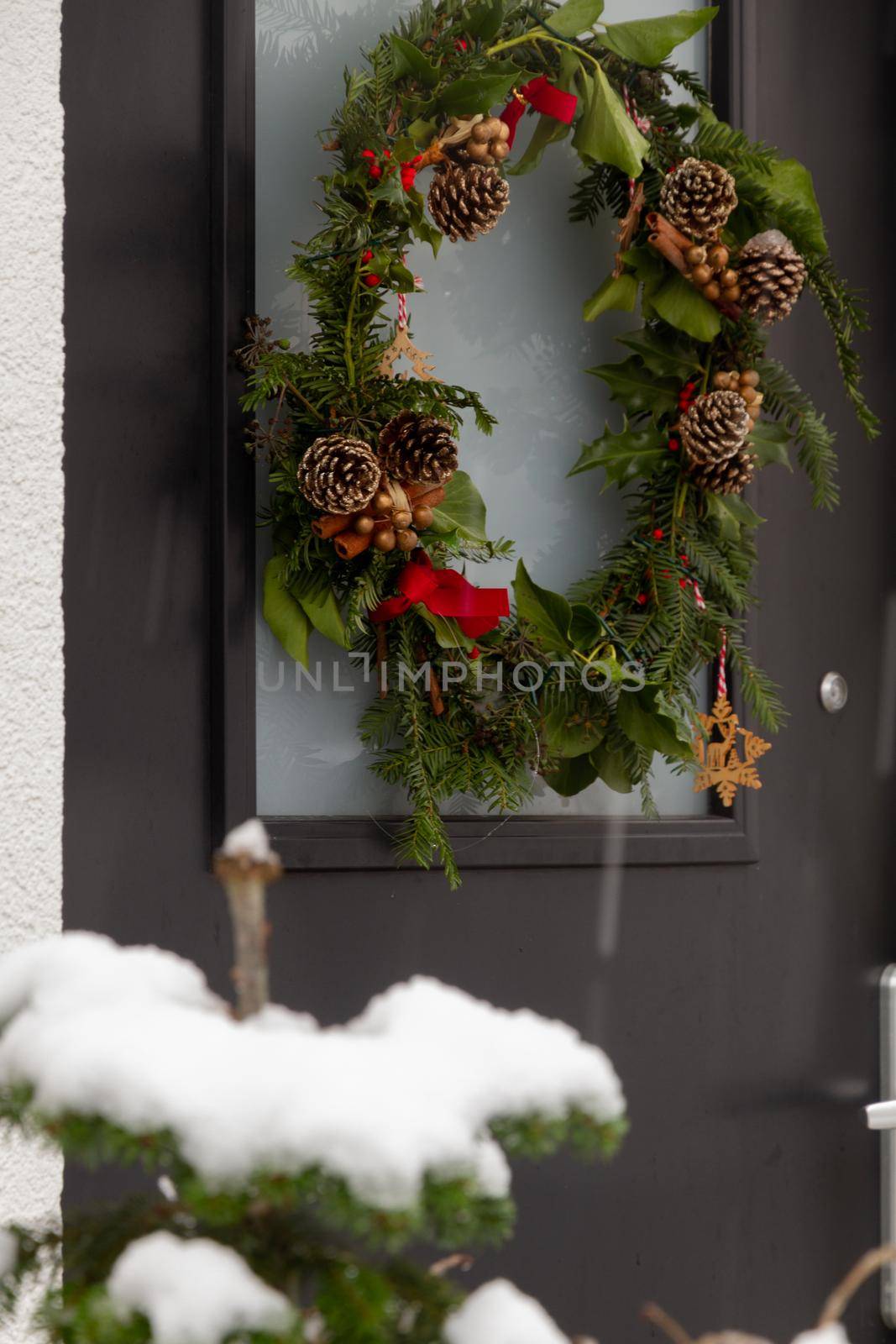 Detail of a Christmas wreath in a black door in a snowy day