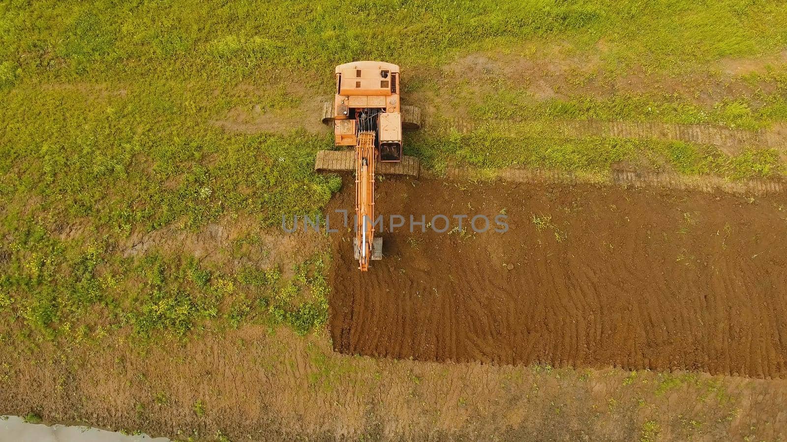 Excavator is digging an irrigation canal. Aerial view:Excavator digging a deep trench.excavator is digging an drainage canal in the agricultural field.