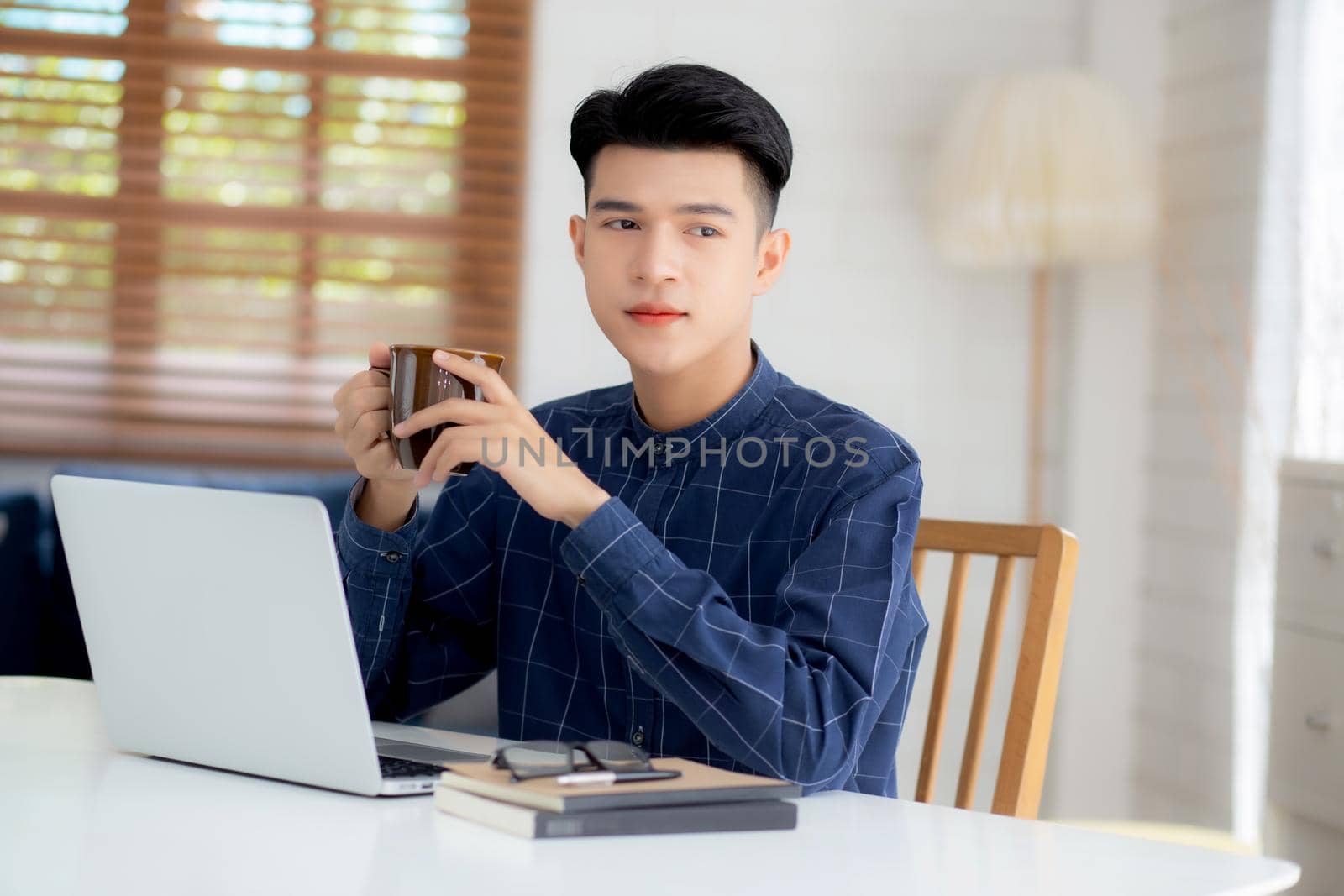 Young business man working from home with laptop computer on desk, freelance male sitting stay home using notebook for communication and relax on table, entrepreneur in startup business, new normal.