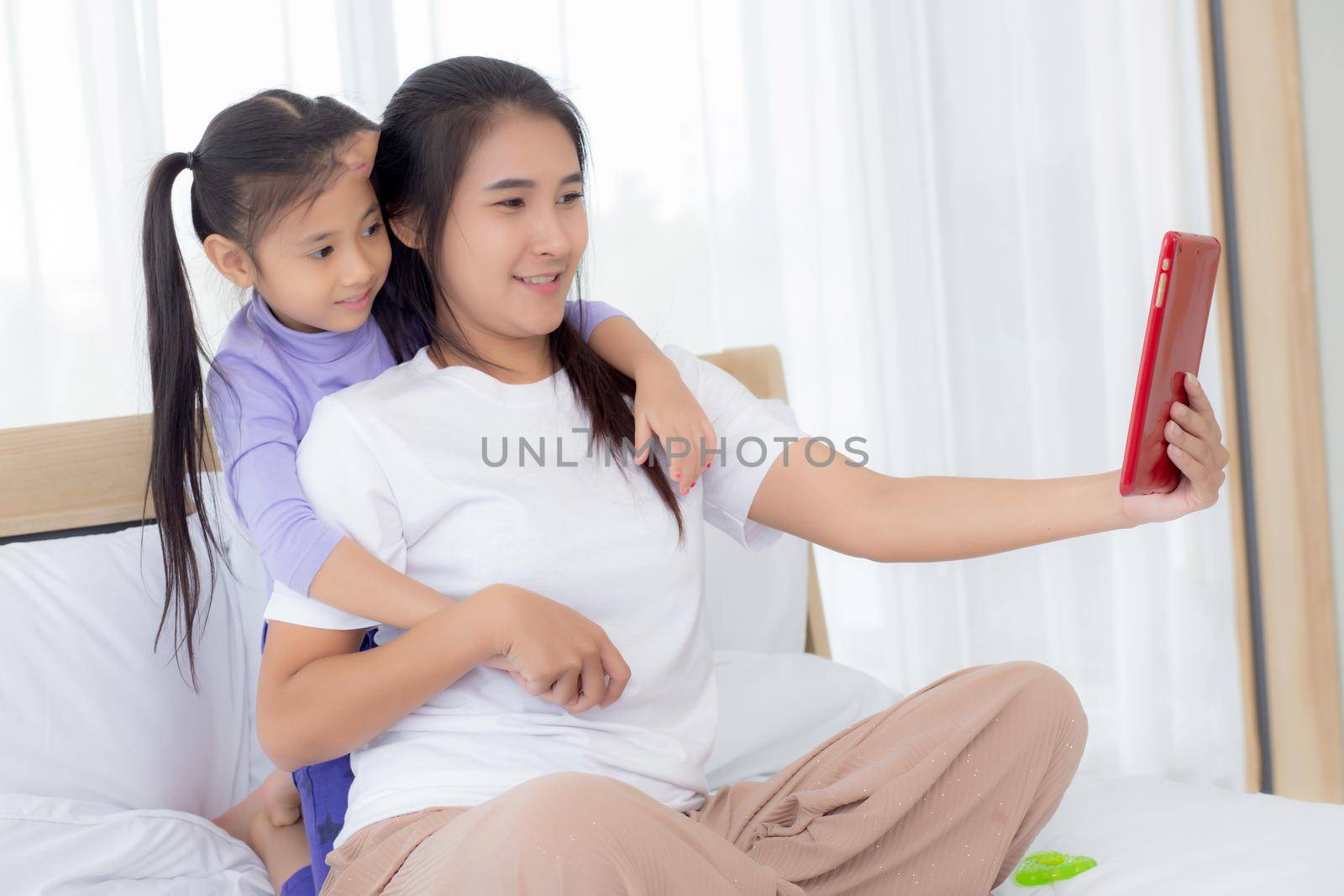 Young asian mom and daughter video call on tablet computer greeting with family together, happy mother and girl with relationship using technology in communication to internet online, two people.