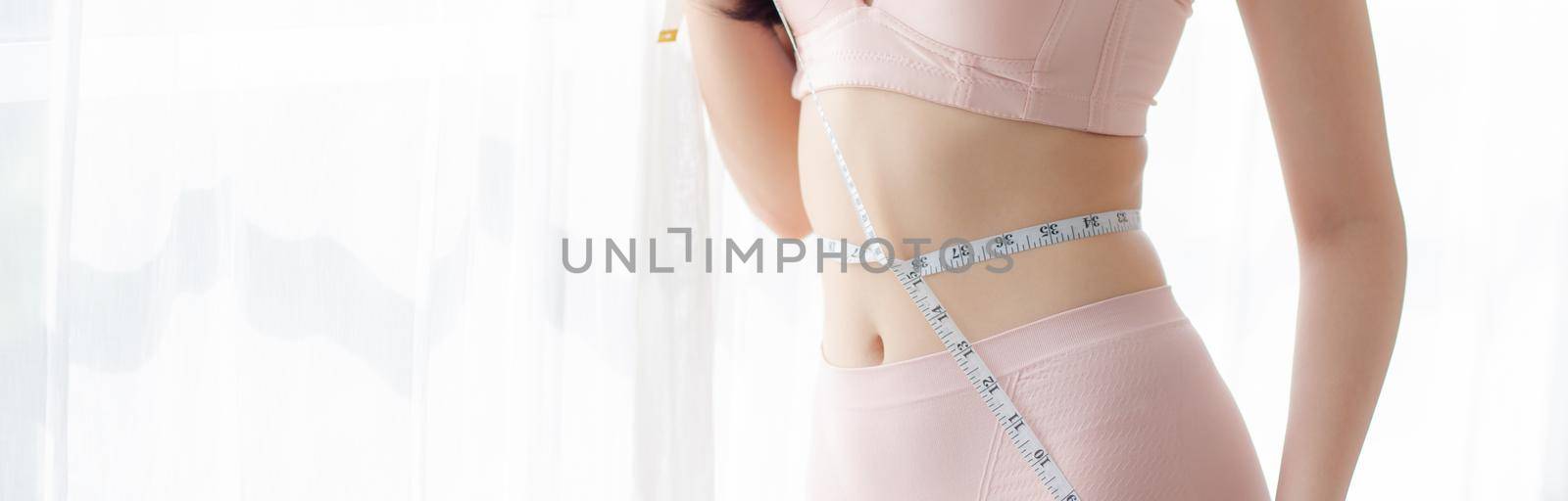 Beautiful young asian woman sexy body slim measuring abdomen for control weight loss in the room, beauty girl belly thin have cellulite with tape measure for diet, health concept, banner website.