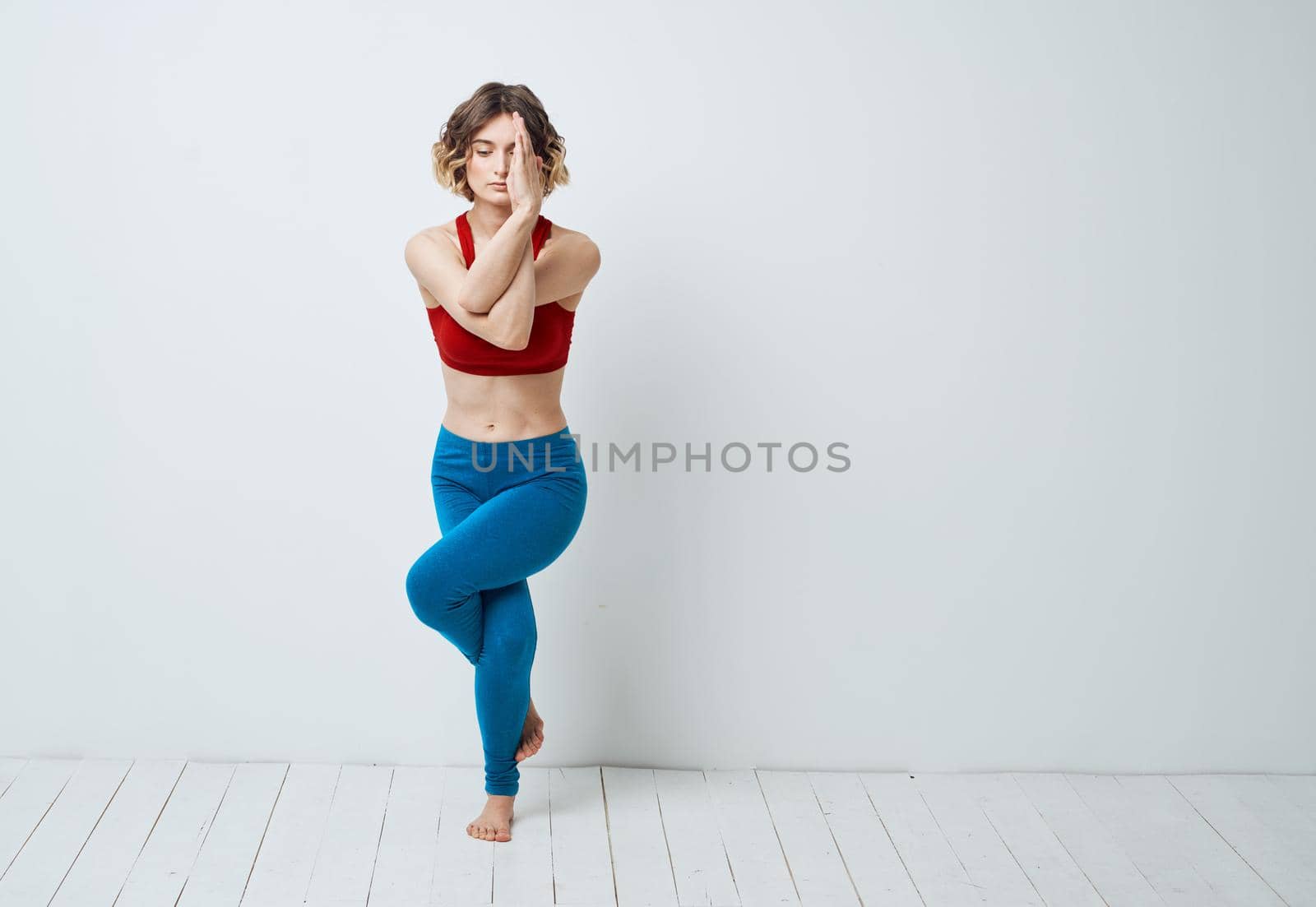 A woman in blue jeans and a red T-shirt goes in for sports on a light background by SHOTPRIME