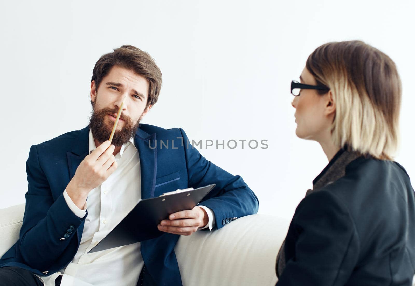 Business man with documents explains something to a young woman Sitting on a sofa indoors. High quality photo