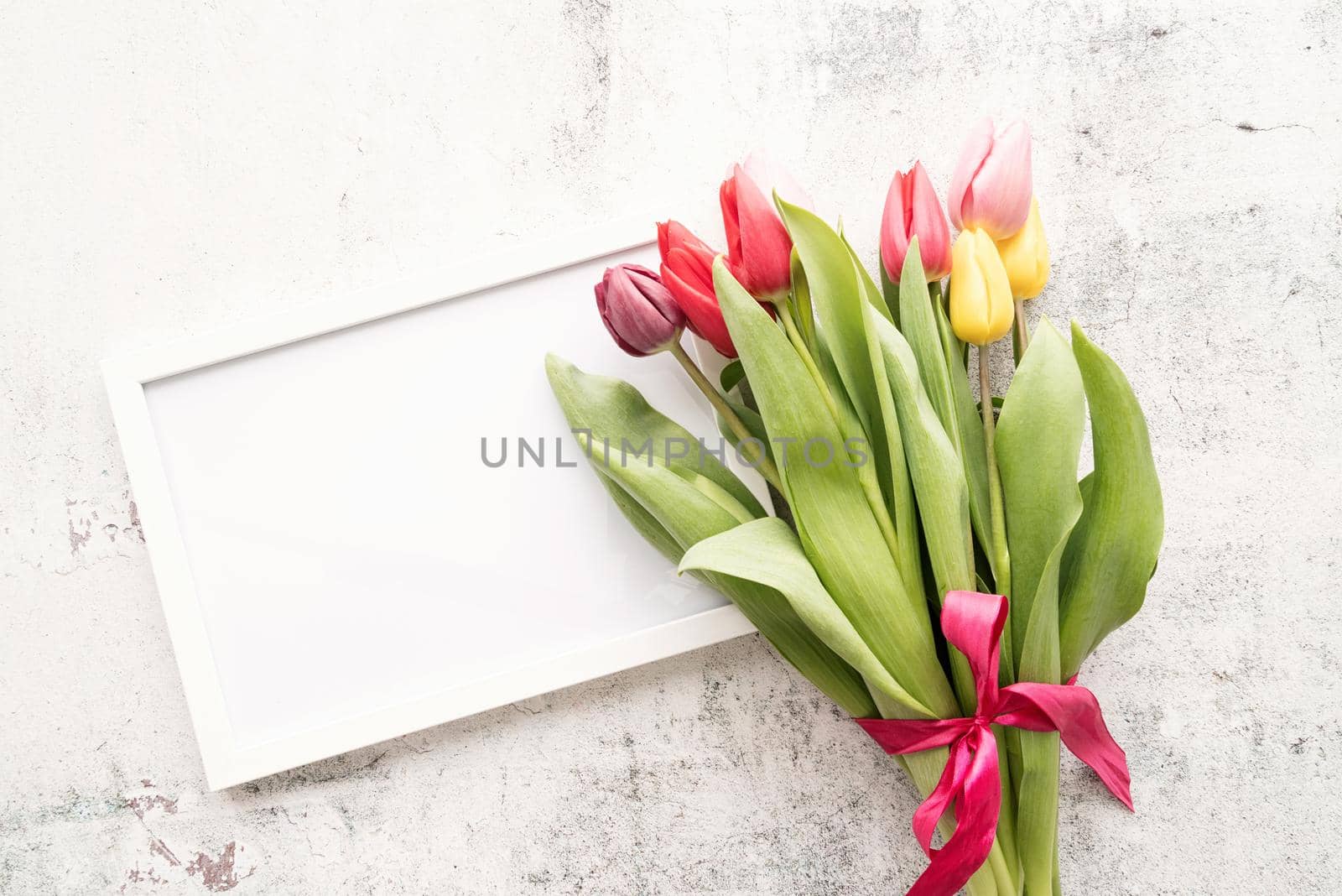 Spring concept. colorfull tulip bouquet and blank frame for mock up design on white background with copy space