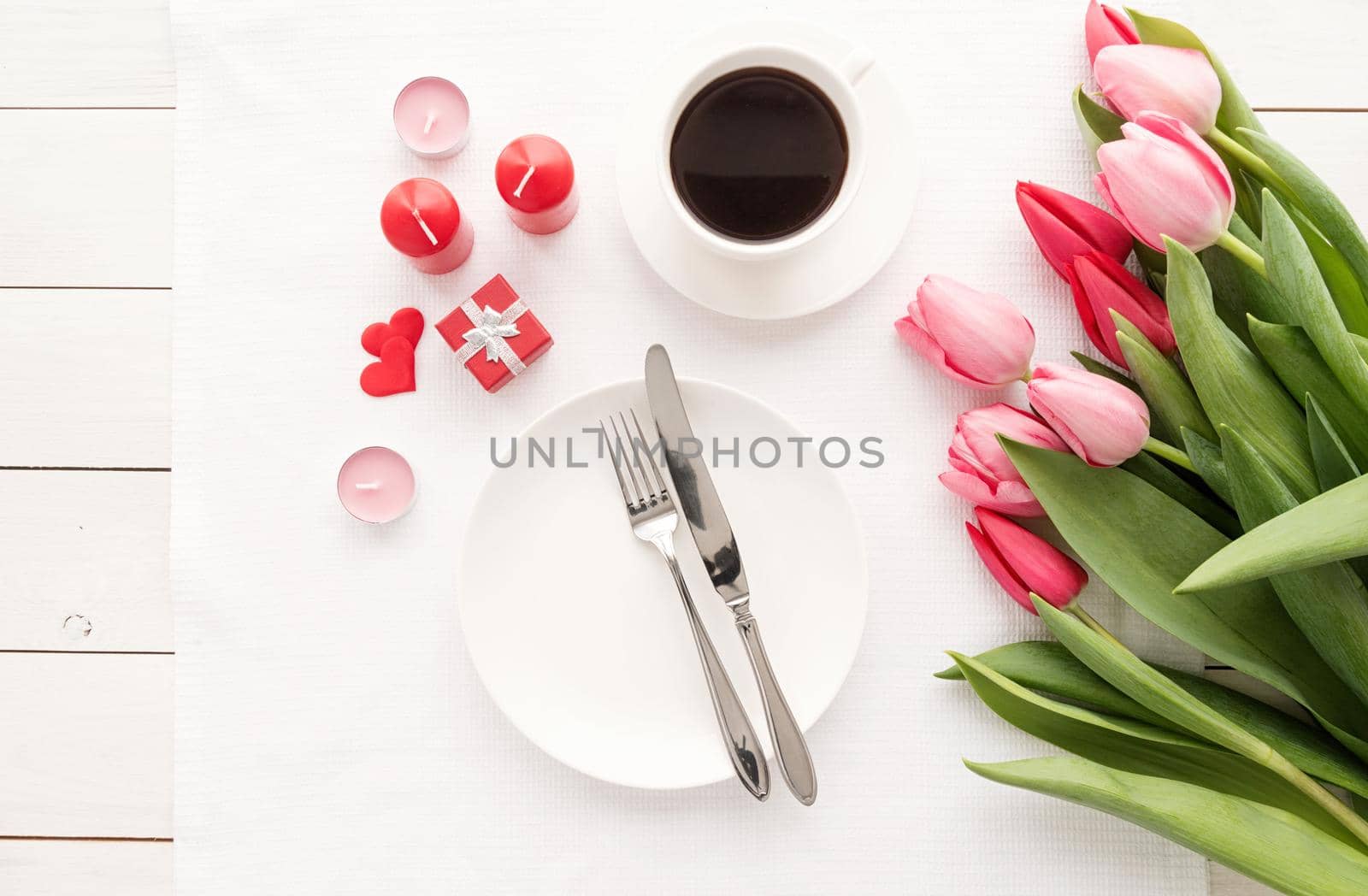 Festive wedding, birthday, romantic table setting with silver cutlery and fresh pink tulips bouquet. Flat lay, top view