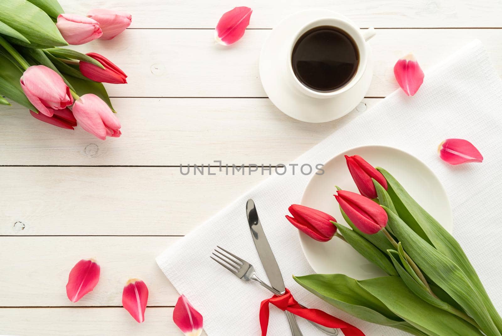 Festive wedding, birthday, romantic table setting with silver cutlery and fresh pink tulips bouquet. Flat lay, top view