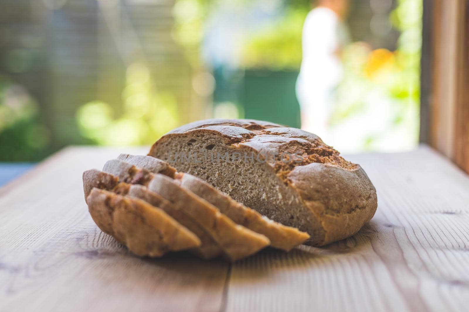 Fresh dark bread in slices, lying on a wooden cutting board. Defocused, blurry background