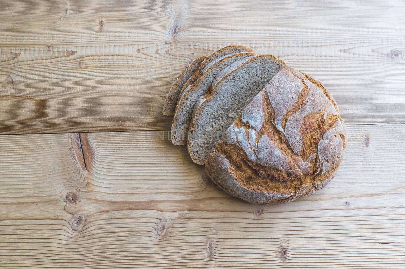 Fresh dark bread in slices, lying on a wooden cutting board.
