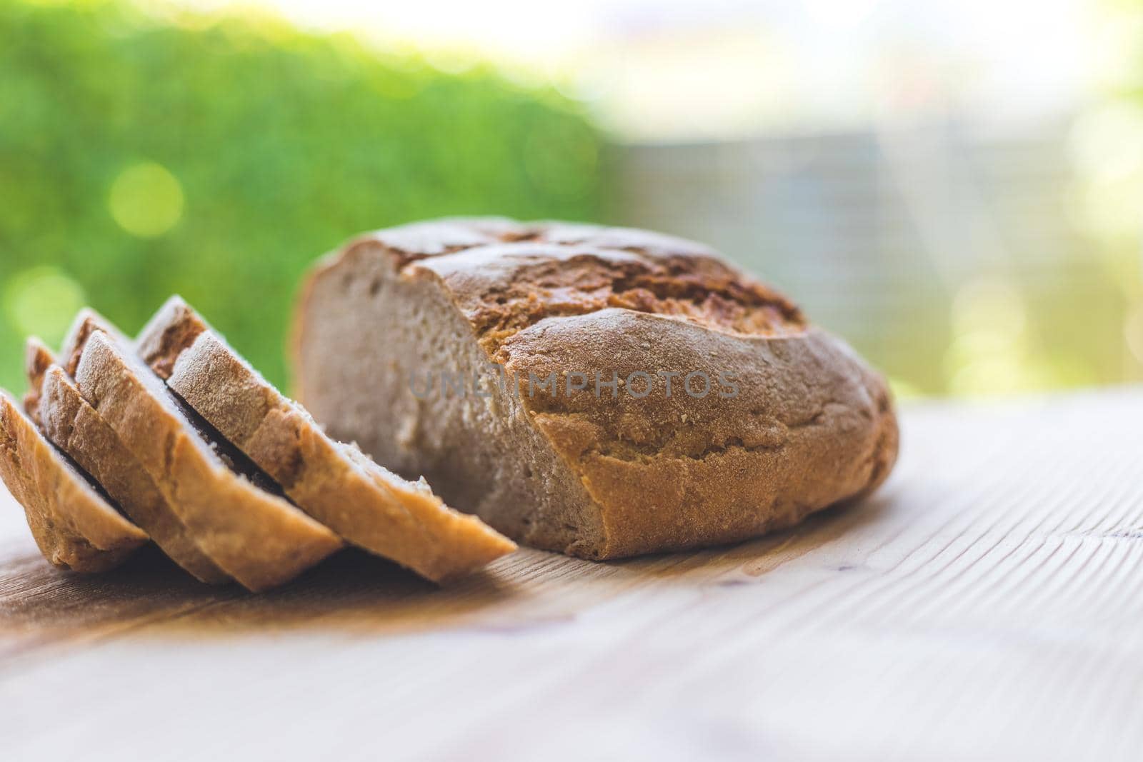 Fresh dark bread in slices, lying on a wooden cutting board. Defocused, blurry background