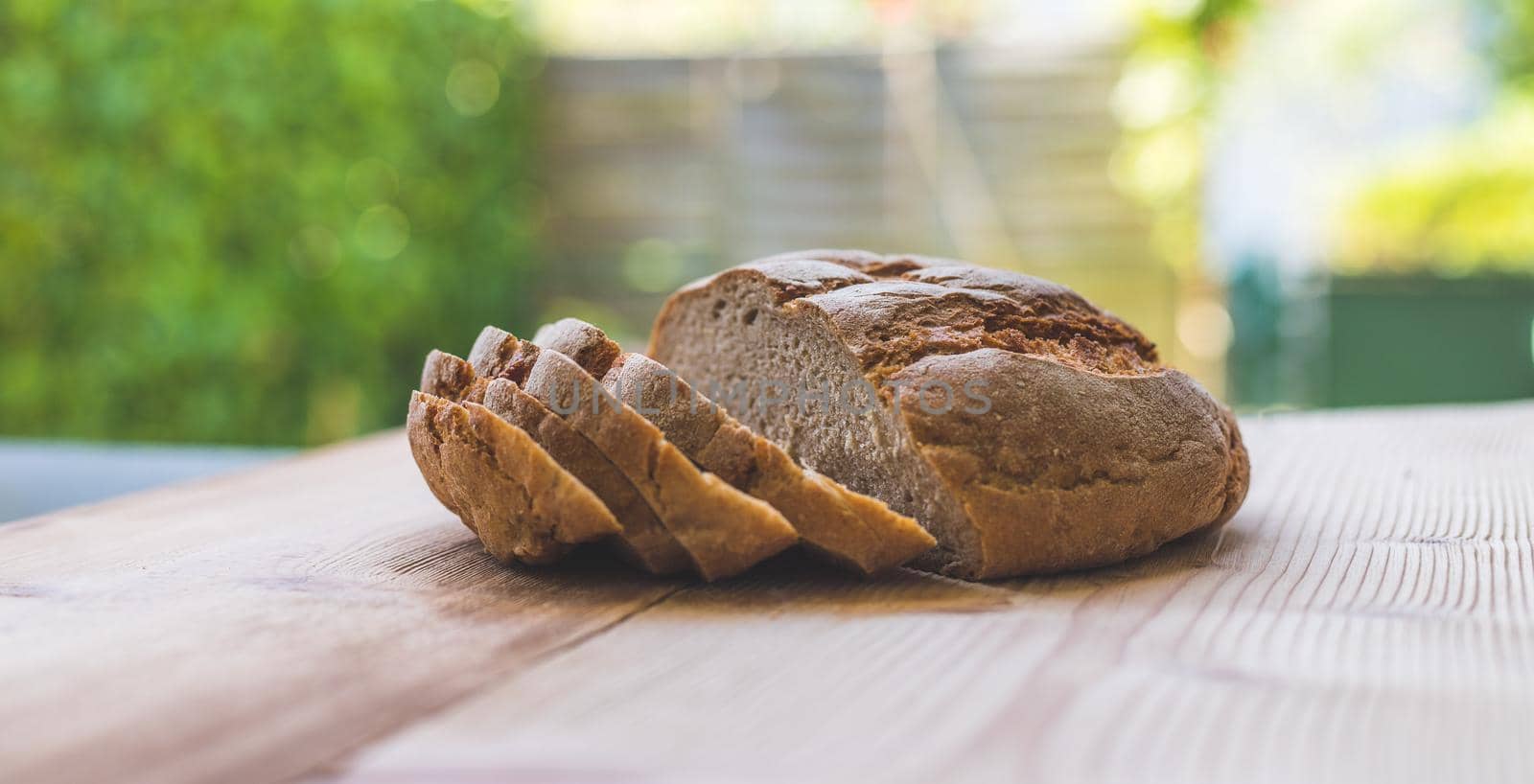 Fresh dark bread in slices, lying on a wooden cutting board. Defocused, blurry background