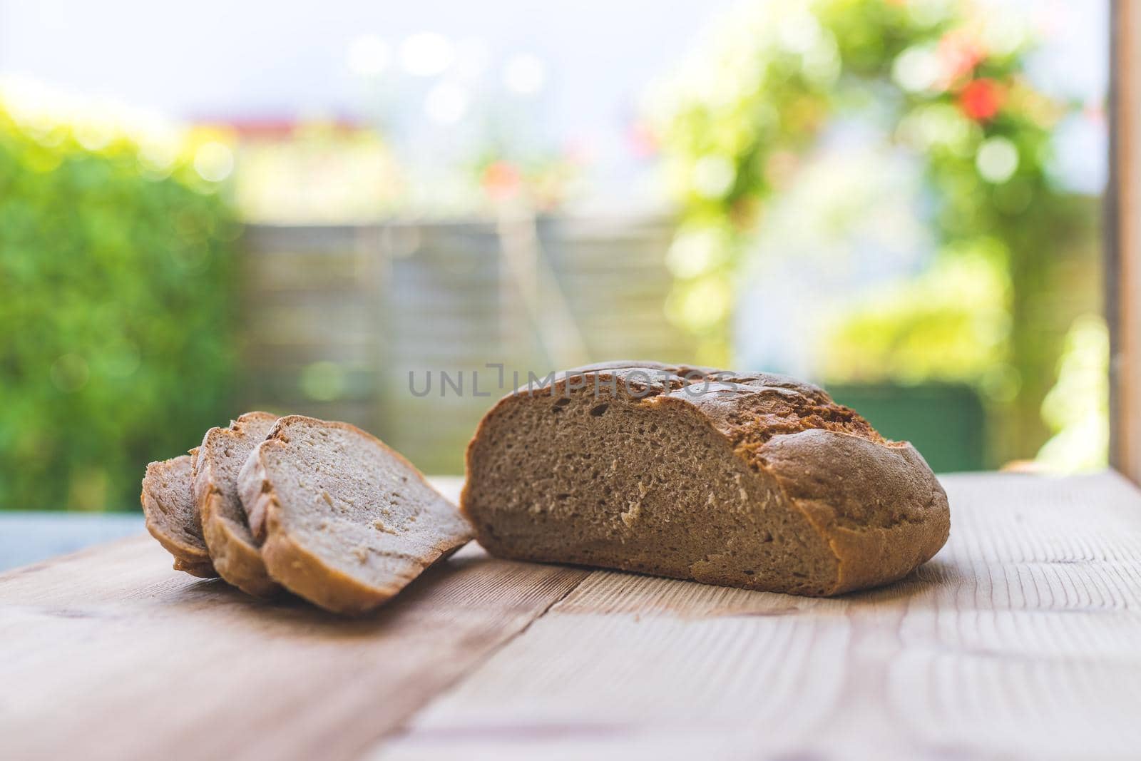 Fresh dark bread in slices, lying on a wooden cutting board. Defocused, blurry background