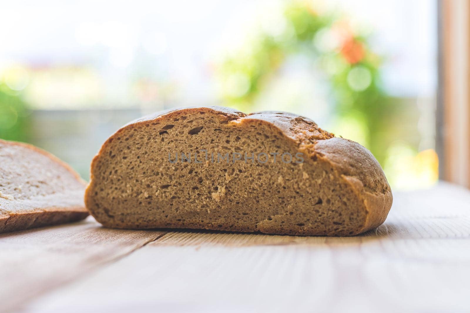 Fresh dark bread in slices, lying on a wooden cutting board. Defocused, blurry background