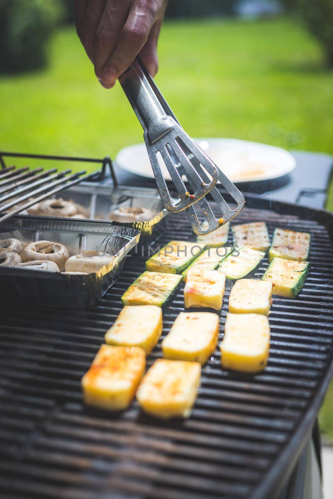 BBQ on weekend. Grill cheese and vegetables on gas grill. Outdoors. by Daxenbichler