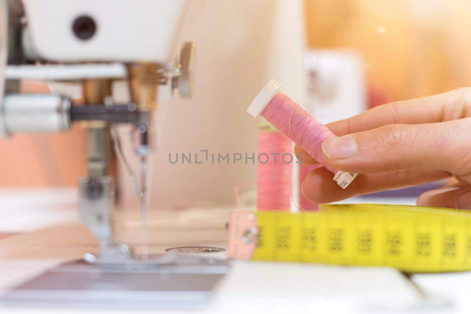 Close up of female hand holding a pink thread in a tailor workshop