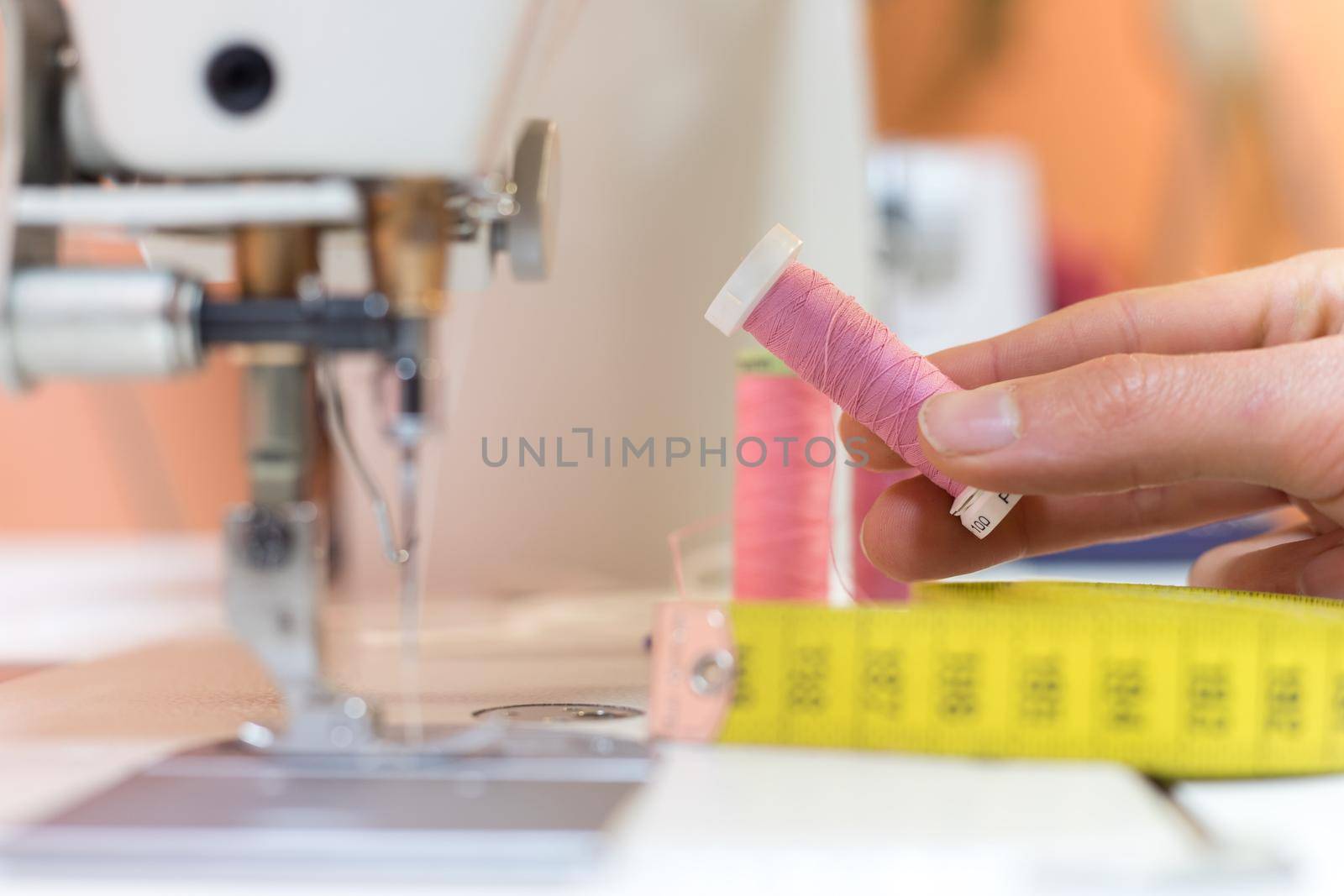 Close up of female hand holding a pink thread in a tailor workshop