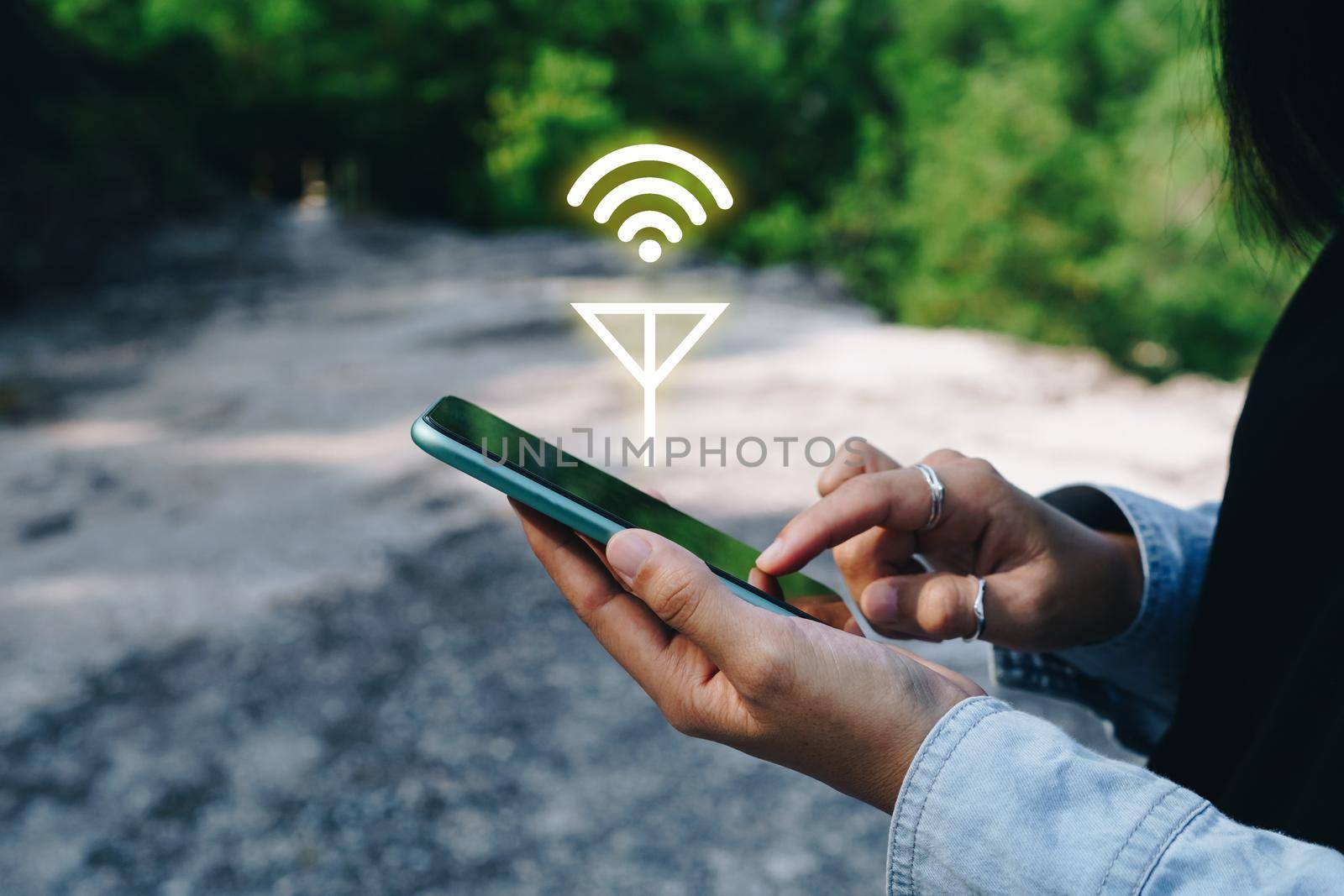 People hand using smartphone looking for signal wifi in off the grid no power space area or in the wood jungle.