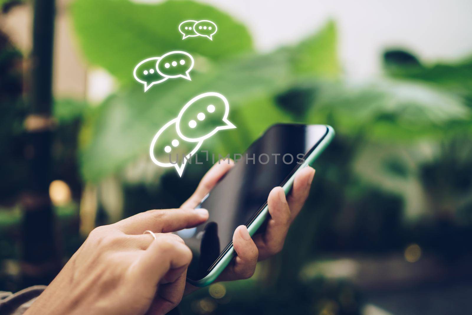 People hand using smartphone typing, chatting or text  messages in chat icons pop up. Social media maketing technology concept. Vintage soft color tone background.