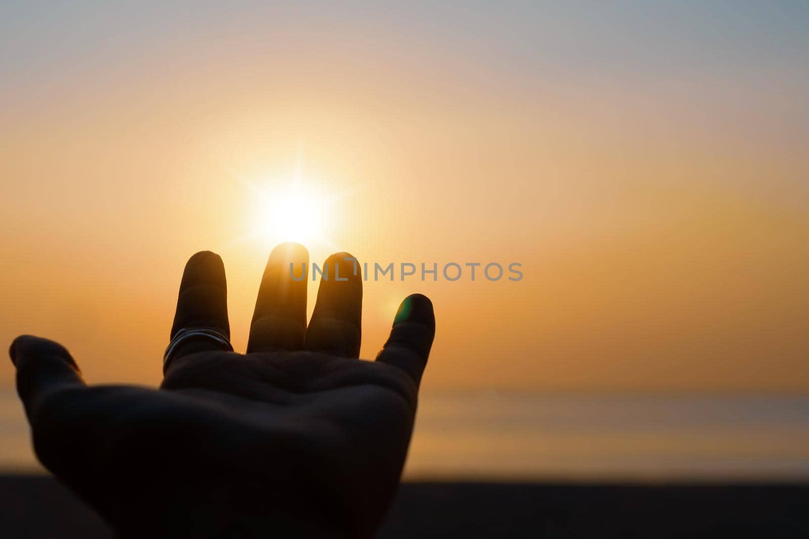 Hand reach out to sunset sky beach sand nature background. Relax and rest in vacation. by Suwant