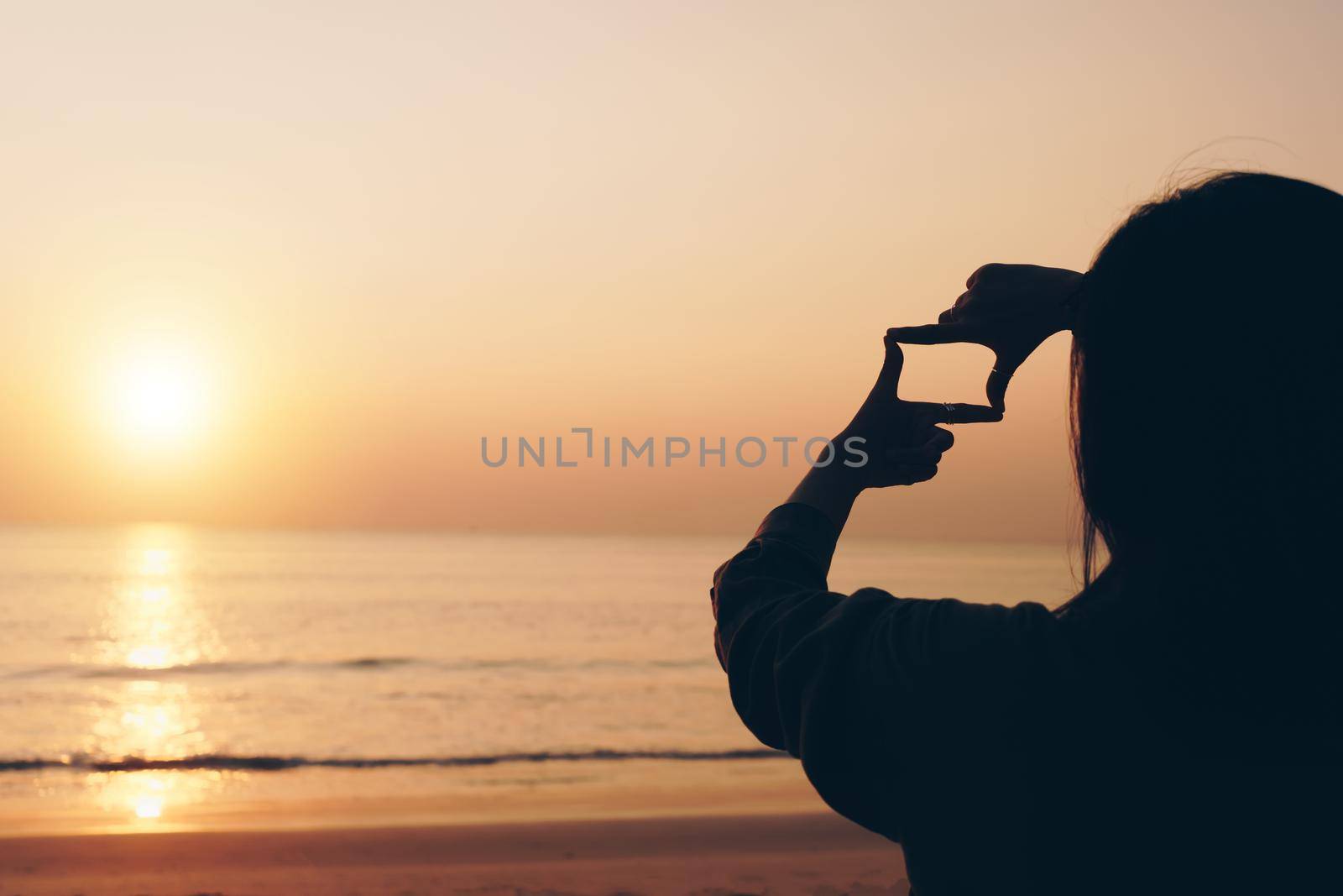 Selective focus of woman hands making frame by finger gesture with sunrise on mountain, Female capture sunrise or sunlight outdoor. Future planning. by Suwant