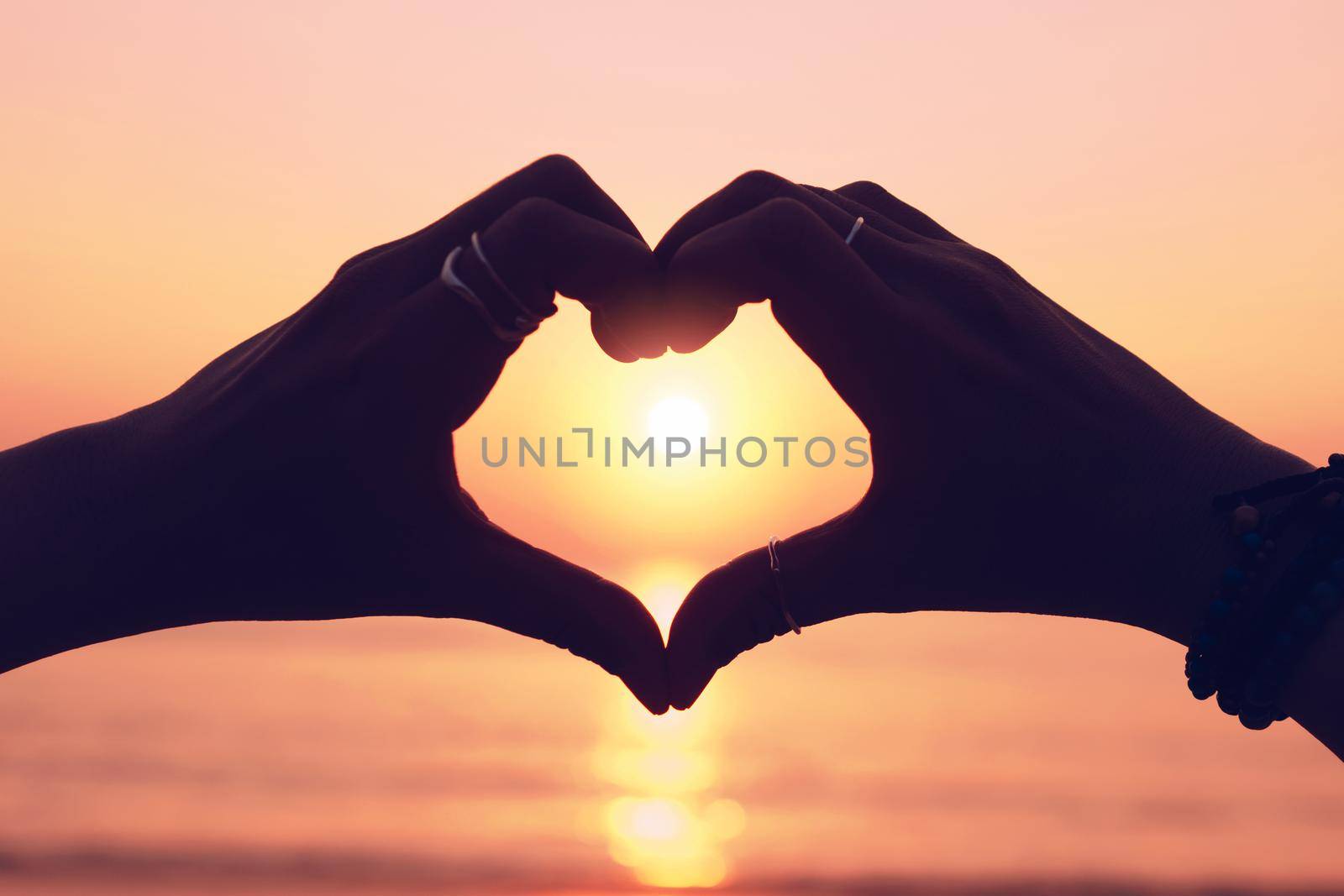 Woman hand do heart shape on sunset sky and bokeh background. love valentine day concept.