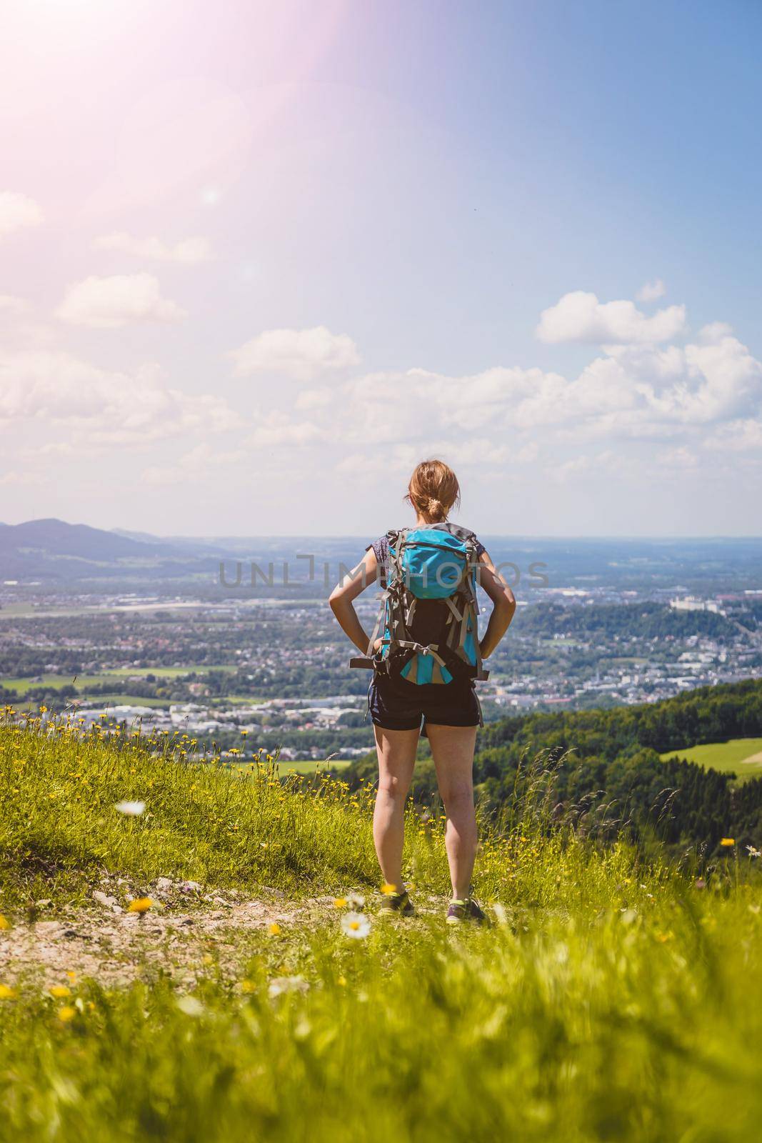 Enjoying the idyllic mountain landscape on Gaisberg: Girl is standing on idyllic meadow and enjoying the view over the far away city of Salzburg by Daxenbichler