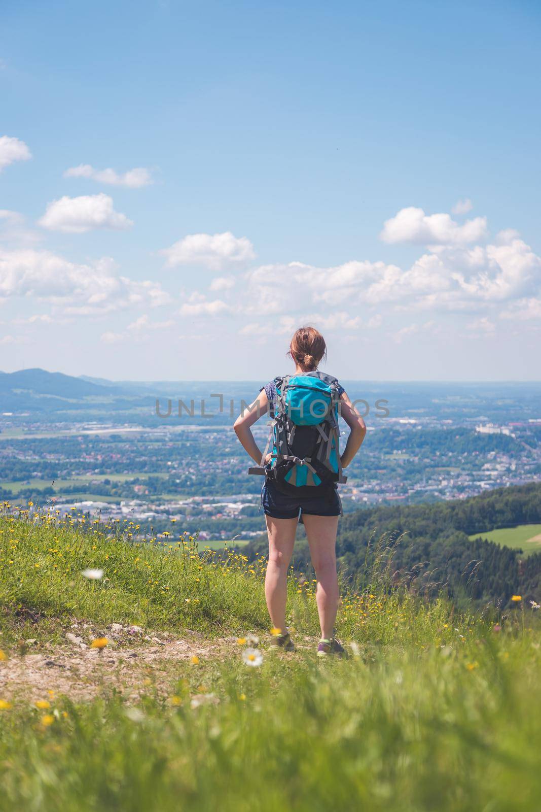 Enjoying the idyllic mountain landscape on Gaisberg: Girl is standing on idyllic meadow and enjoying the view over the far away city of Salzburg by Daxenbichler