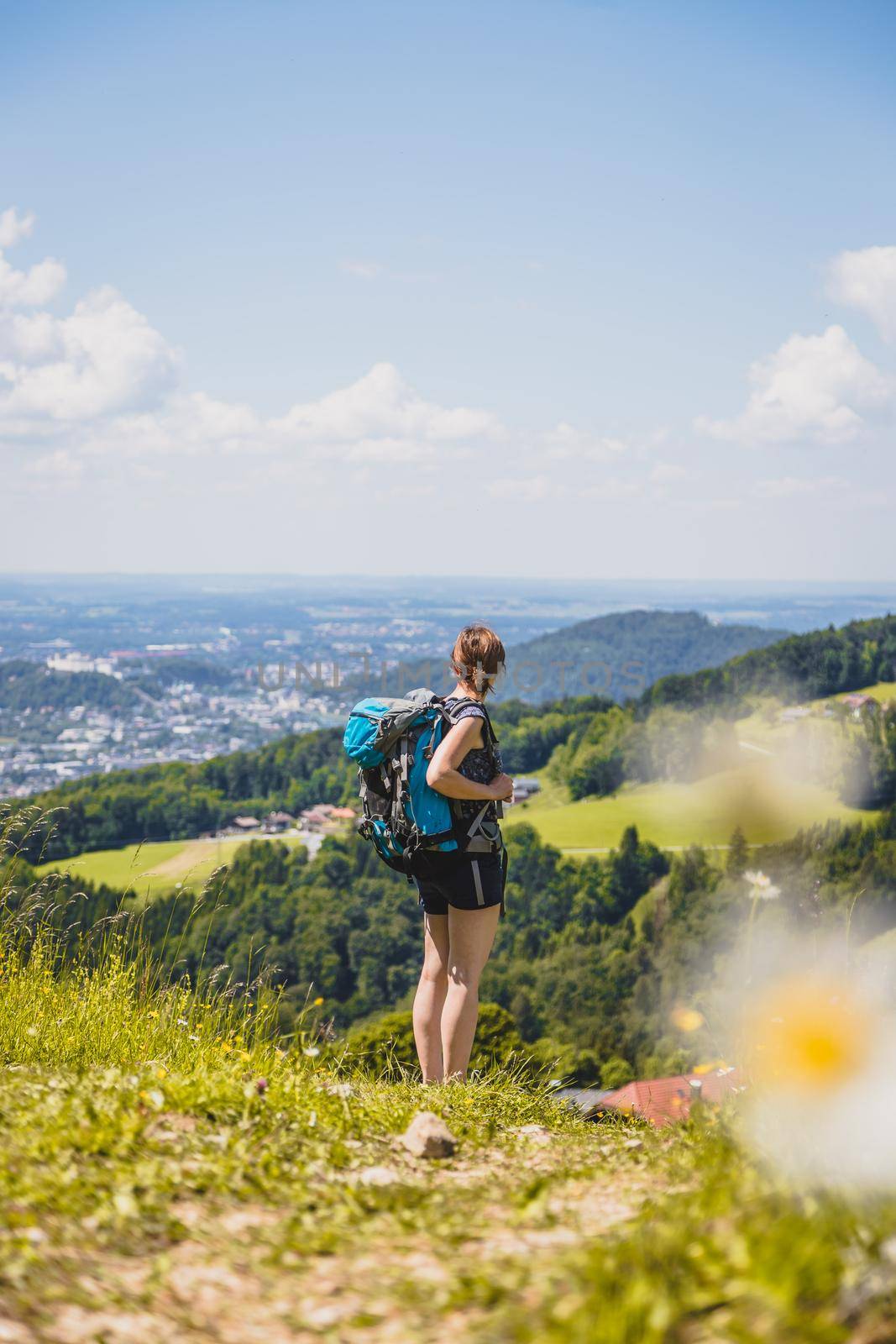 Enjoying the idyllic mountain landscape on Gaisberg: Girl is standing on idyllic meadow and enjoying the view over the far away city of Salzburg by Daxenbichler