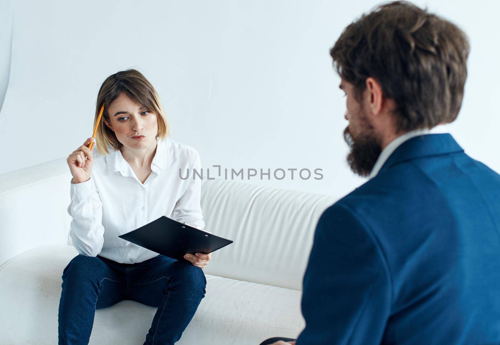 Business man in a classic suit and a woman on the couch with documents in the hands of a psychologist working. High quality photo