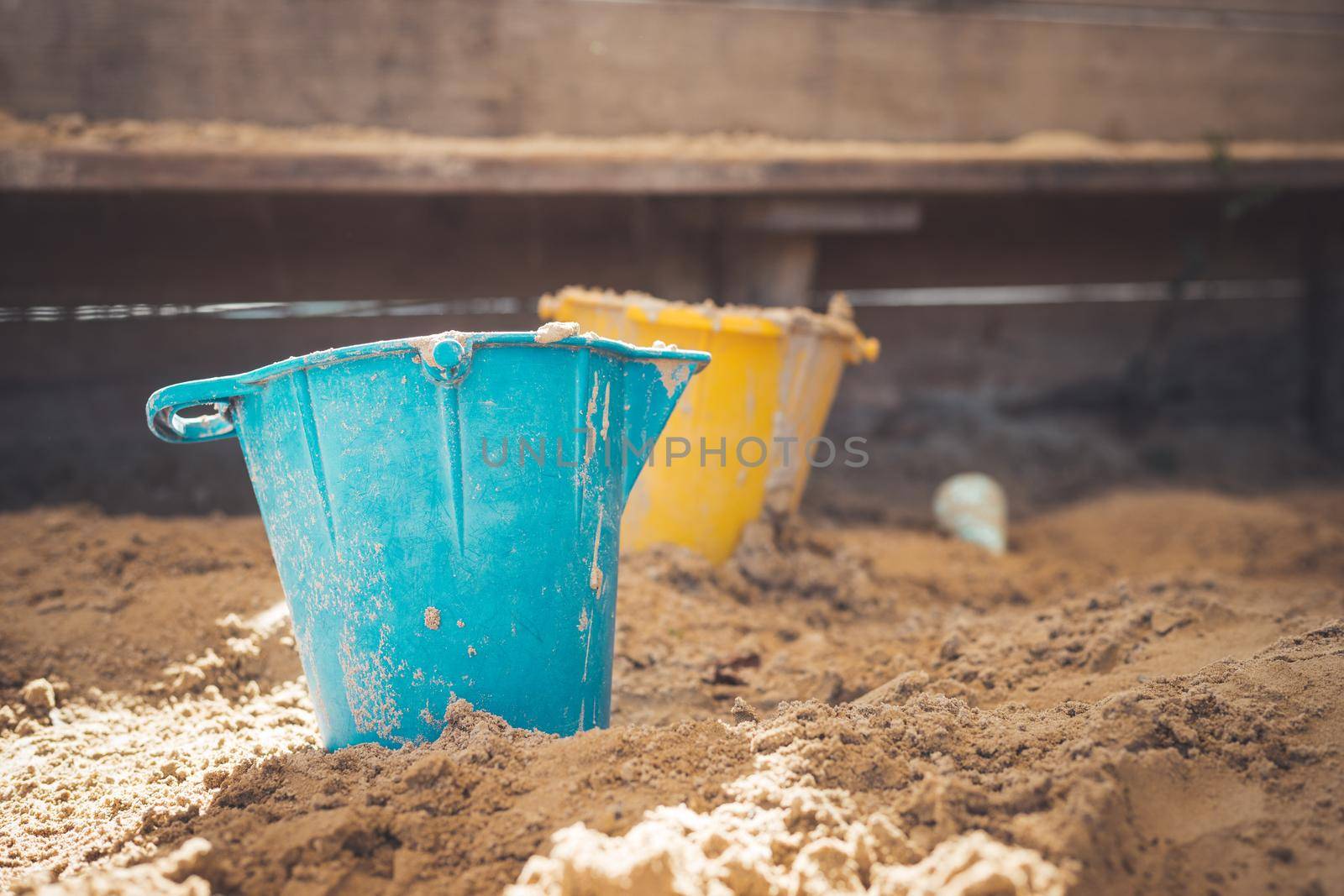 Children plastic toys in the sand box. Dirt bucket, selective focus.