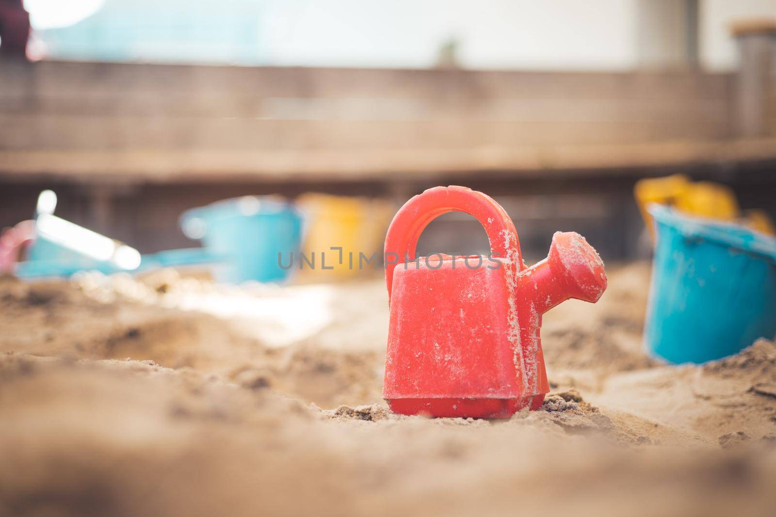 Children plastic toys in the sand box. Watering can, selective focus.