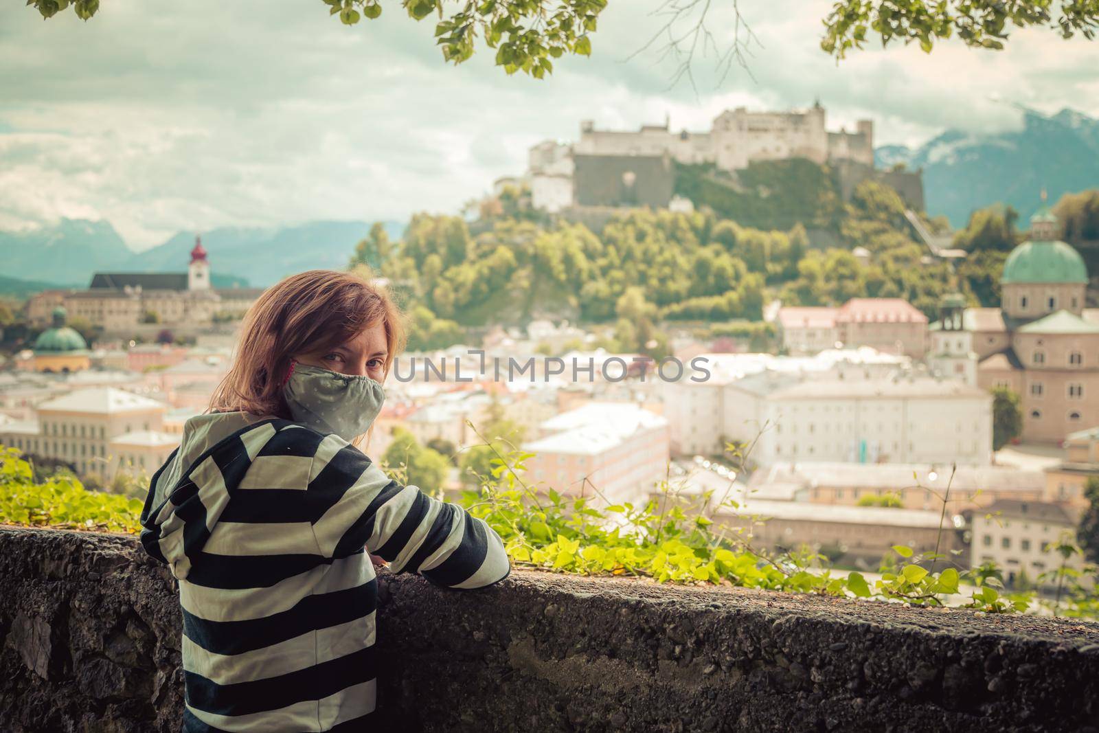 Female tourist with face mask is enjoying the view over the historic district of Salzburg