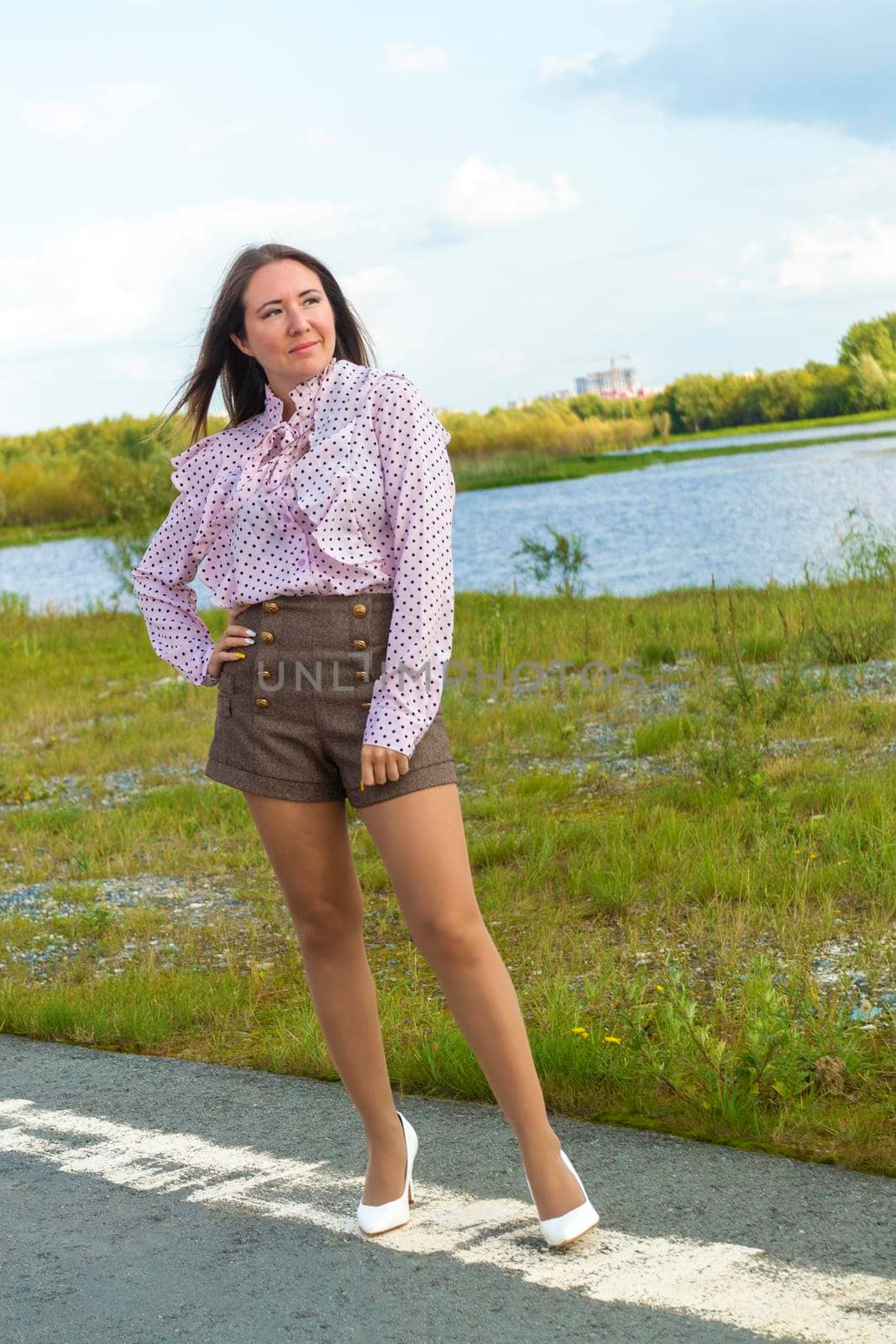 Woman stands on pavement of road on river Shore. In the vicinity of the city of Surgut. Siberia. by Essffes