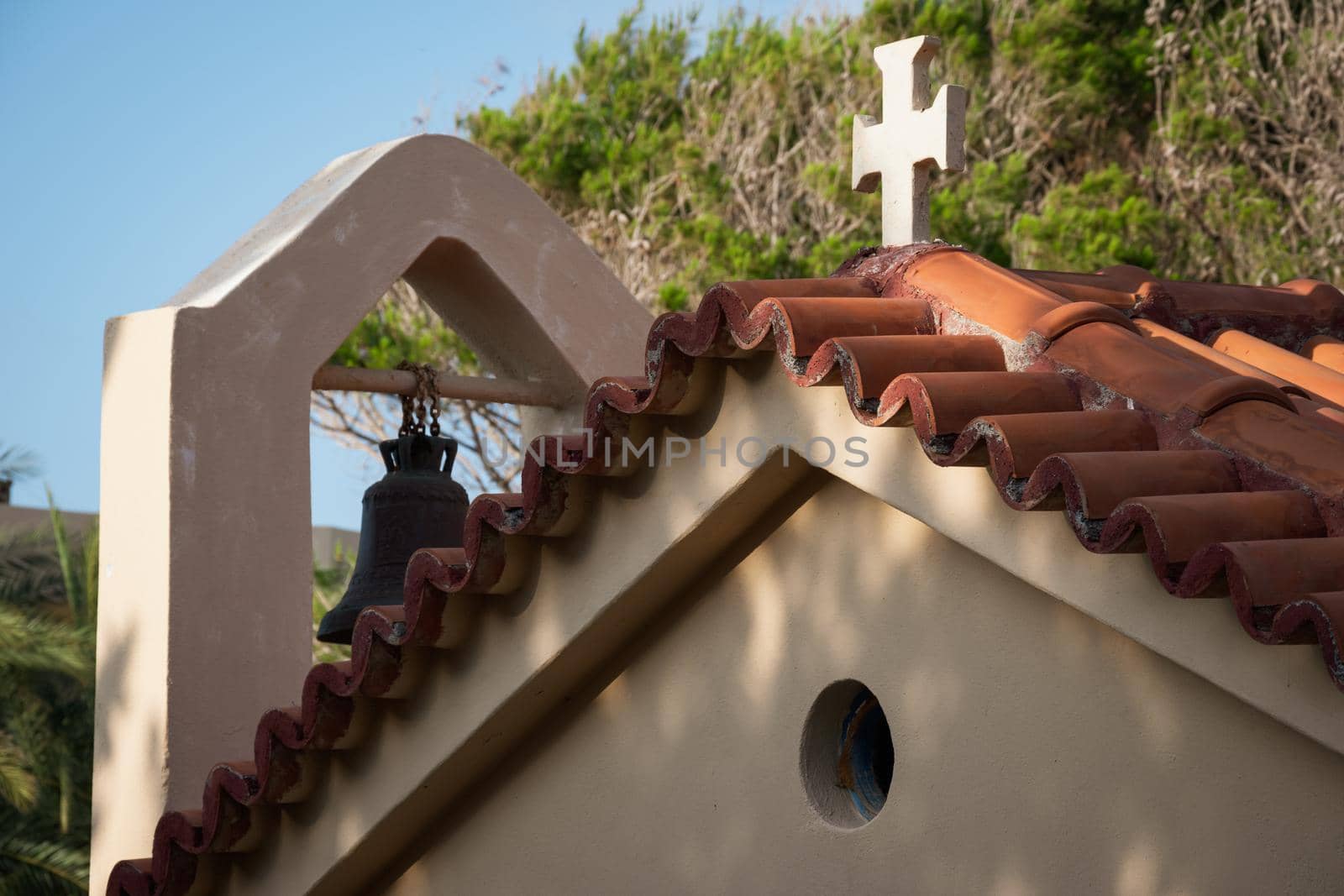 Roof of a beautiful house with a cross and a bell on it in Malia, Crete, Greece by wektorygrafika
