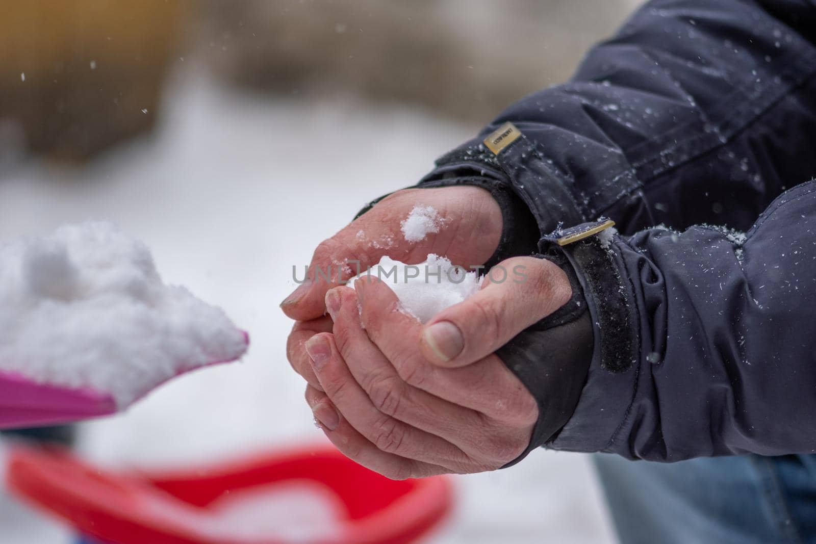 Closeup view of a person making a snowball in his hands standing outside dressed for winter by wektorygrafika