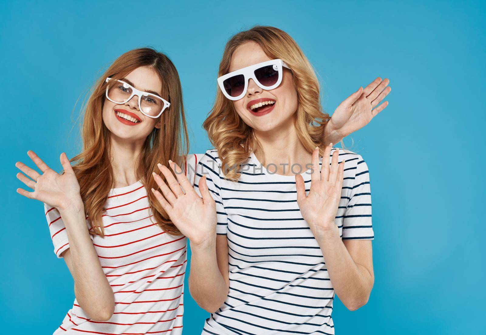 two pretty women gesticulate with hands fun friendship joy lifestyle blue background by SHOTPRIME