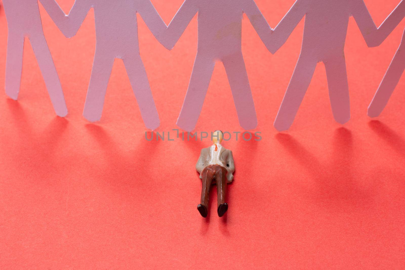 man figurine before Group of paper chain people holding hand by berkay