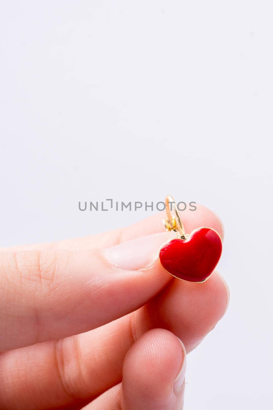 Red color heart shape earring in hand on white