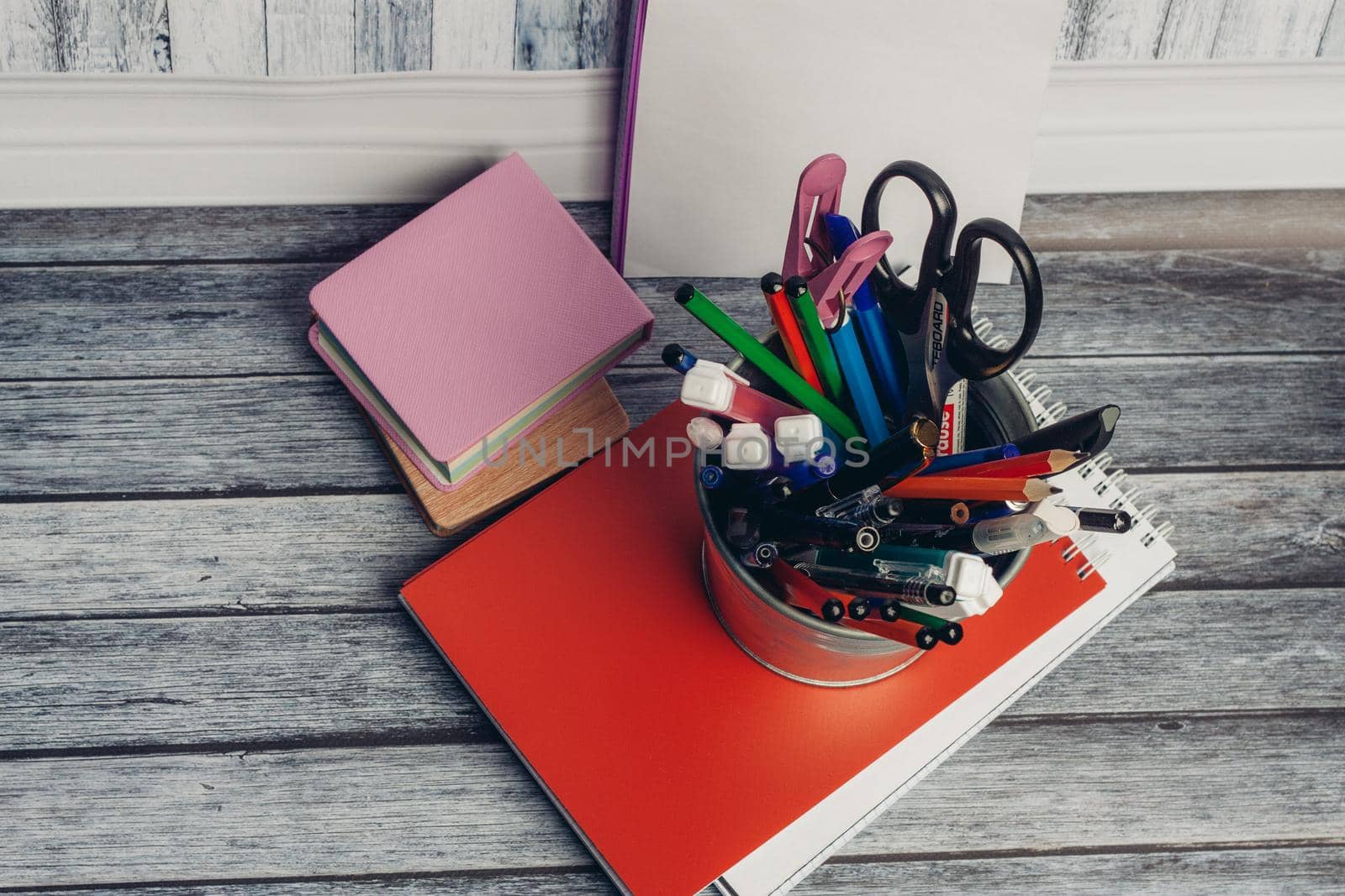 mug with stationery on notepad and wooden table in office. High quality photo