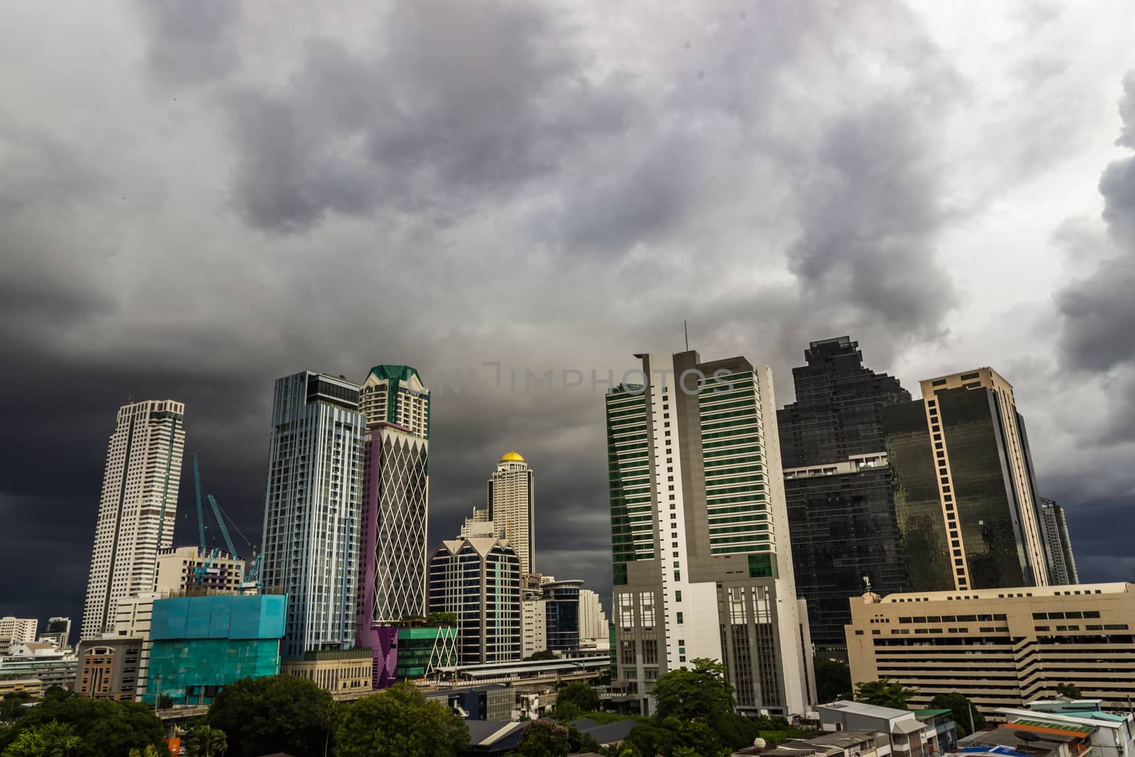 Dark storm clouds before rain of Bangkok city with district office building and center for business in the evening. Selective focus.