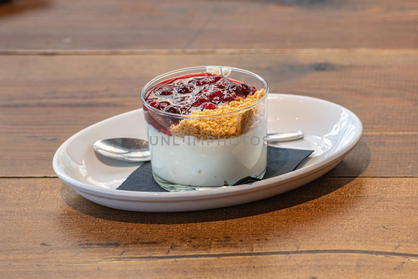 Cheesecake served in a glass with a berry sauce.