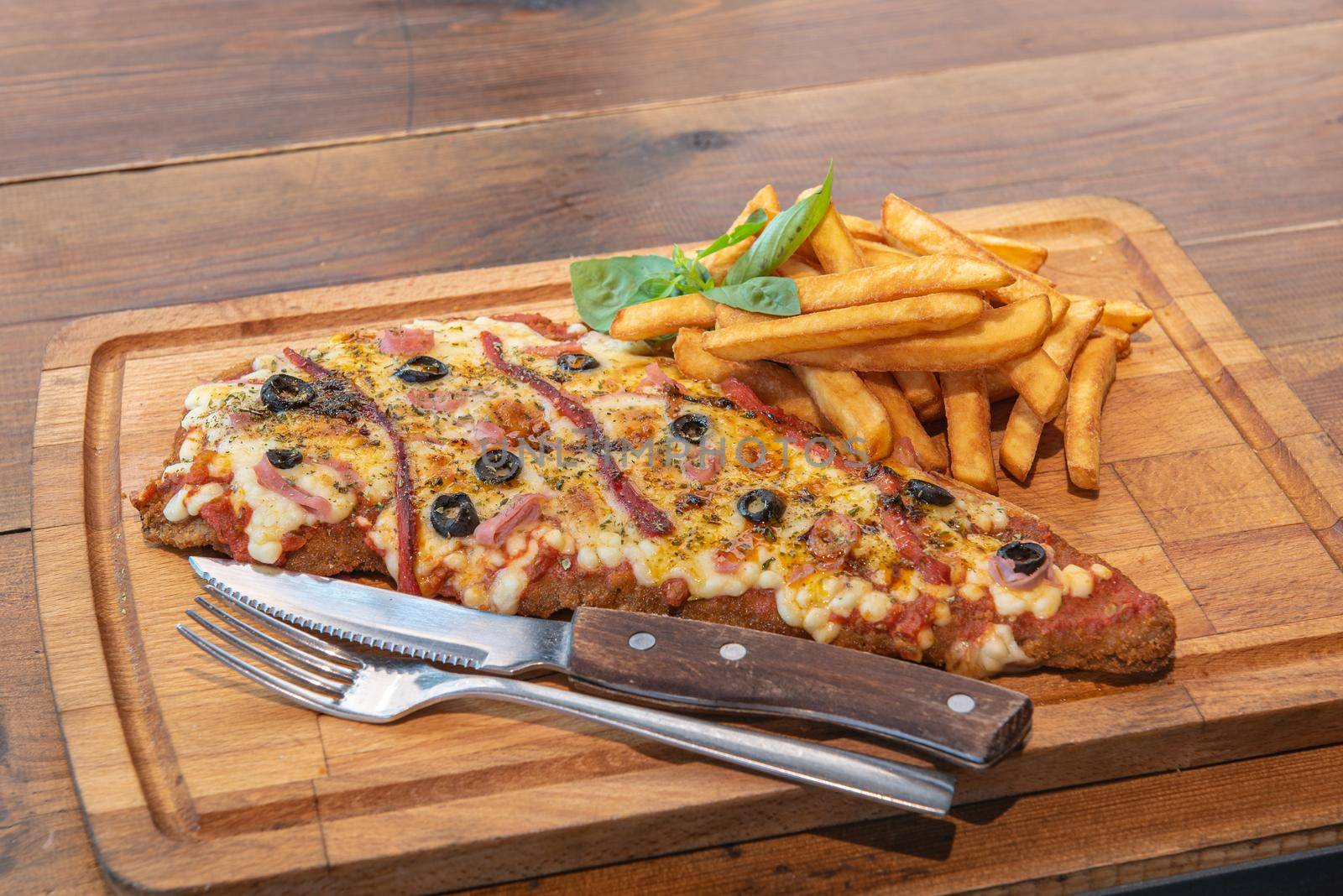 Typical Neapolitan Milanese typical food from Argentina and Uruguay served with French fries and on wooden board.