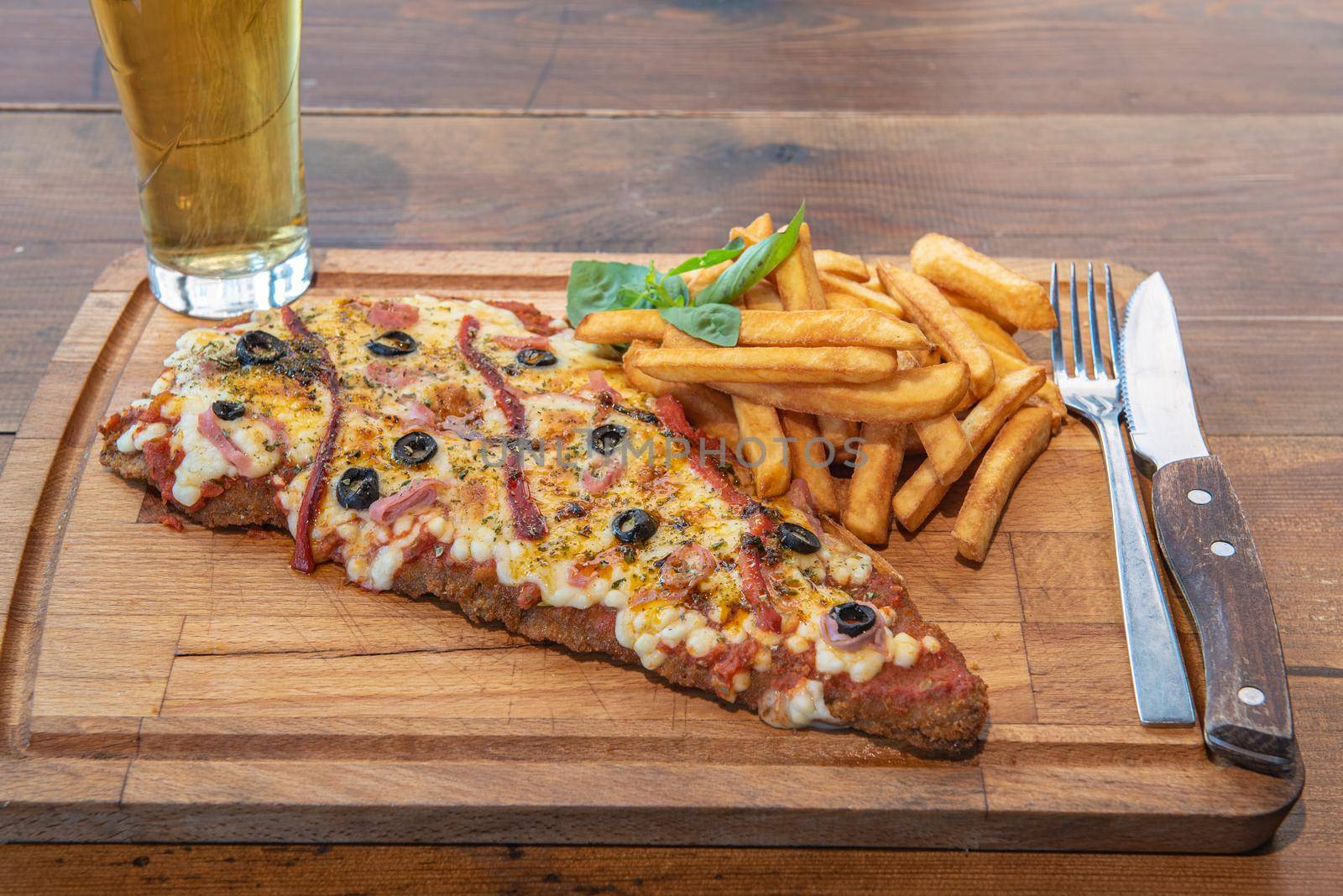 Typical Neapolitan Milanese typical food from Argentina and Uruguay served with French fries and on wooden board.