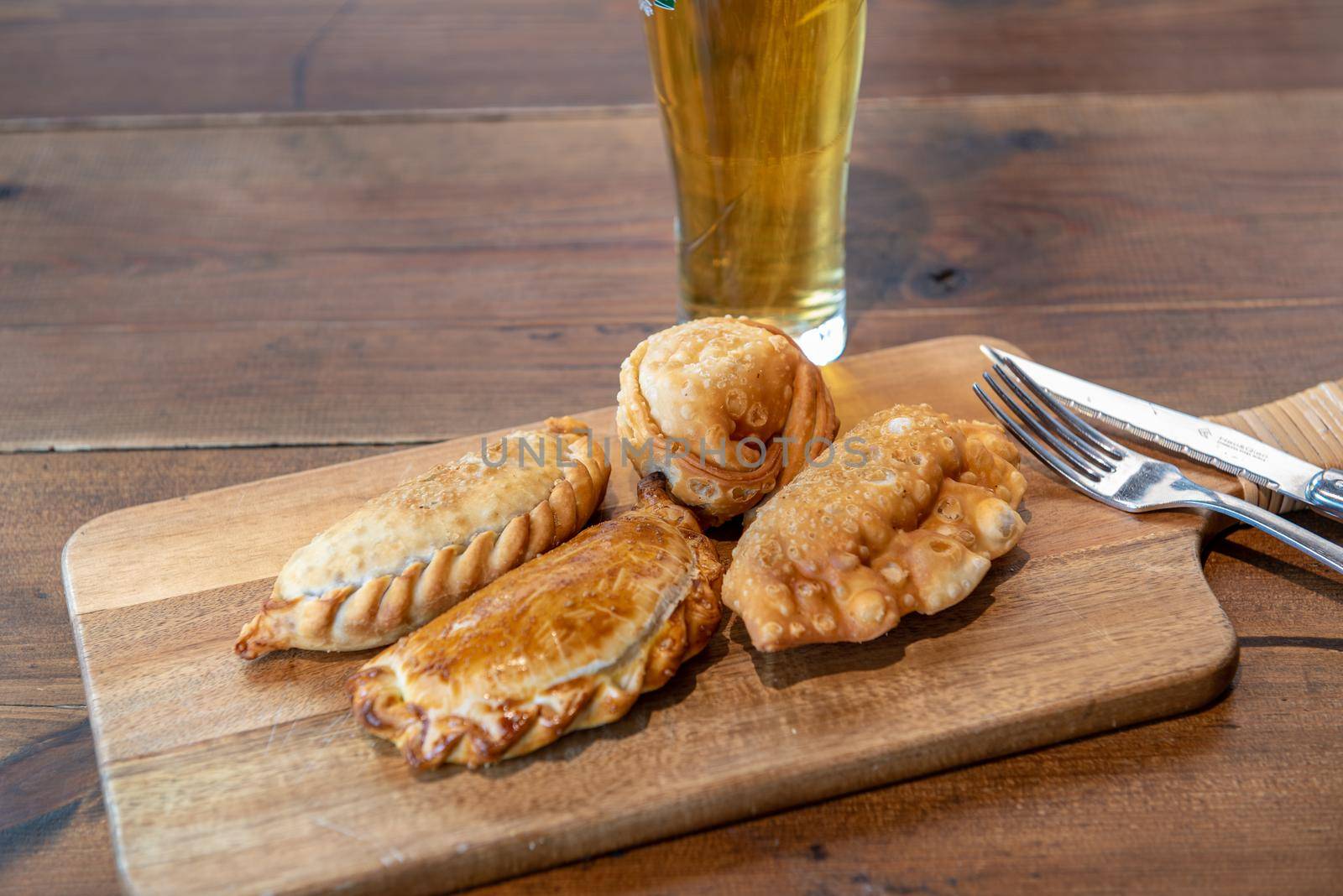 Varied Argentine empanadas with different fillings on a wooden board.