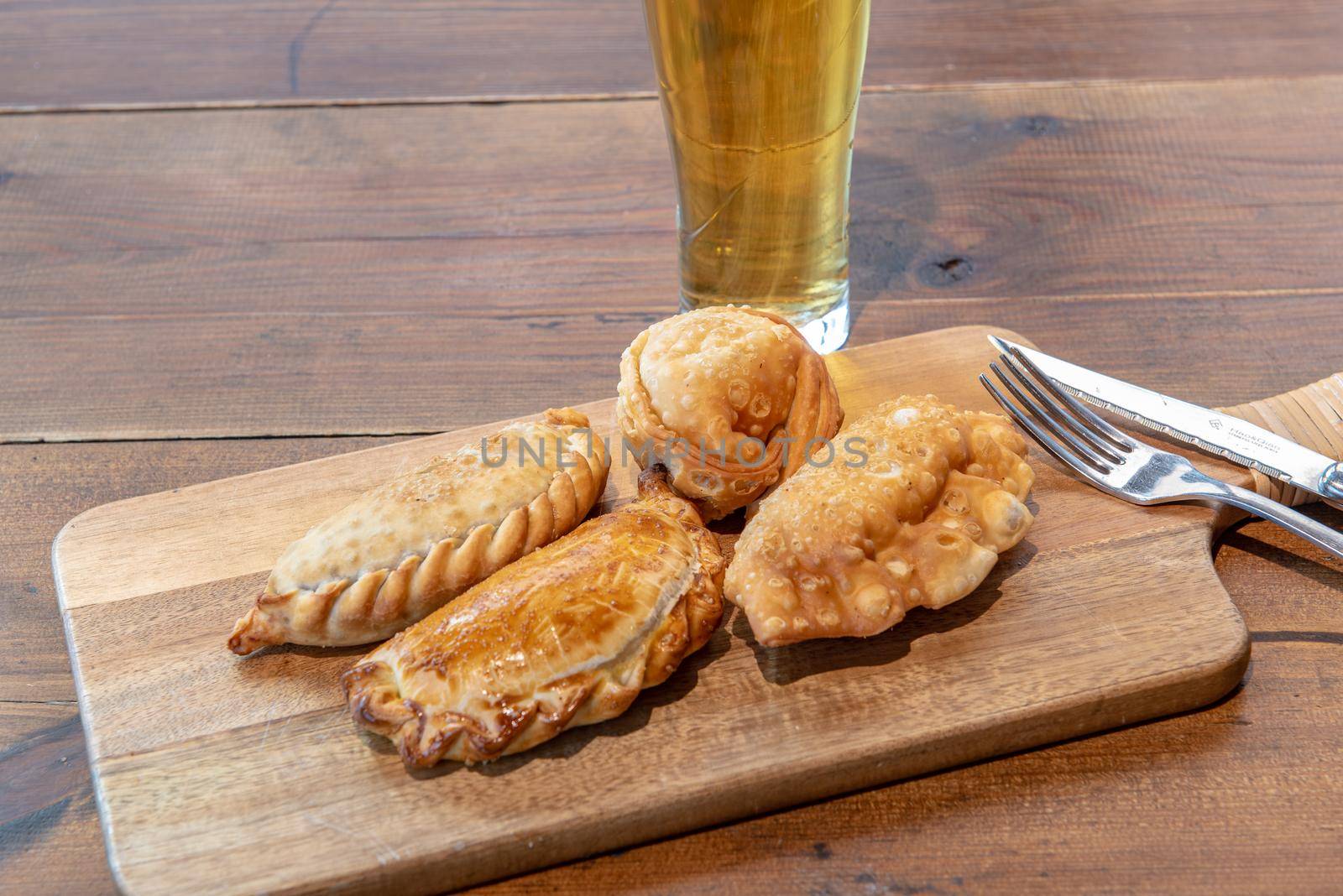 Varied Argentine empanadas with different fillings on a wooden board.
