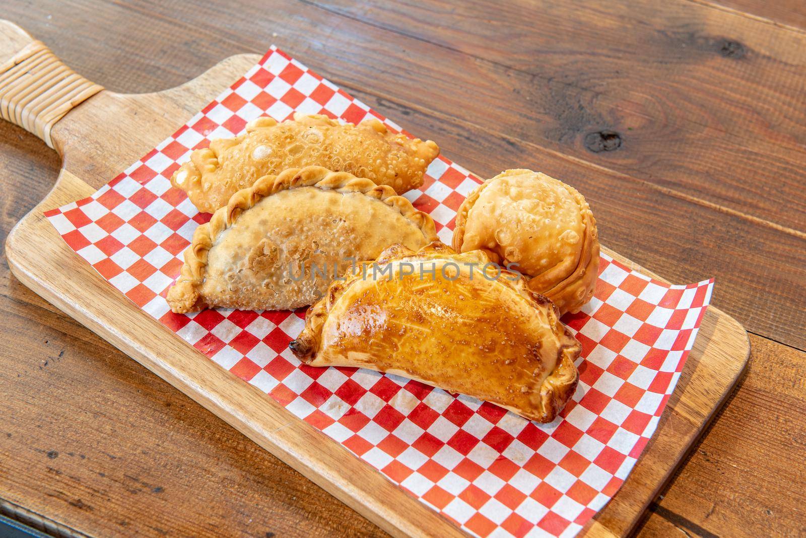 Varied Argentine empanadas with different fillings on a wooden board.